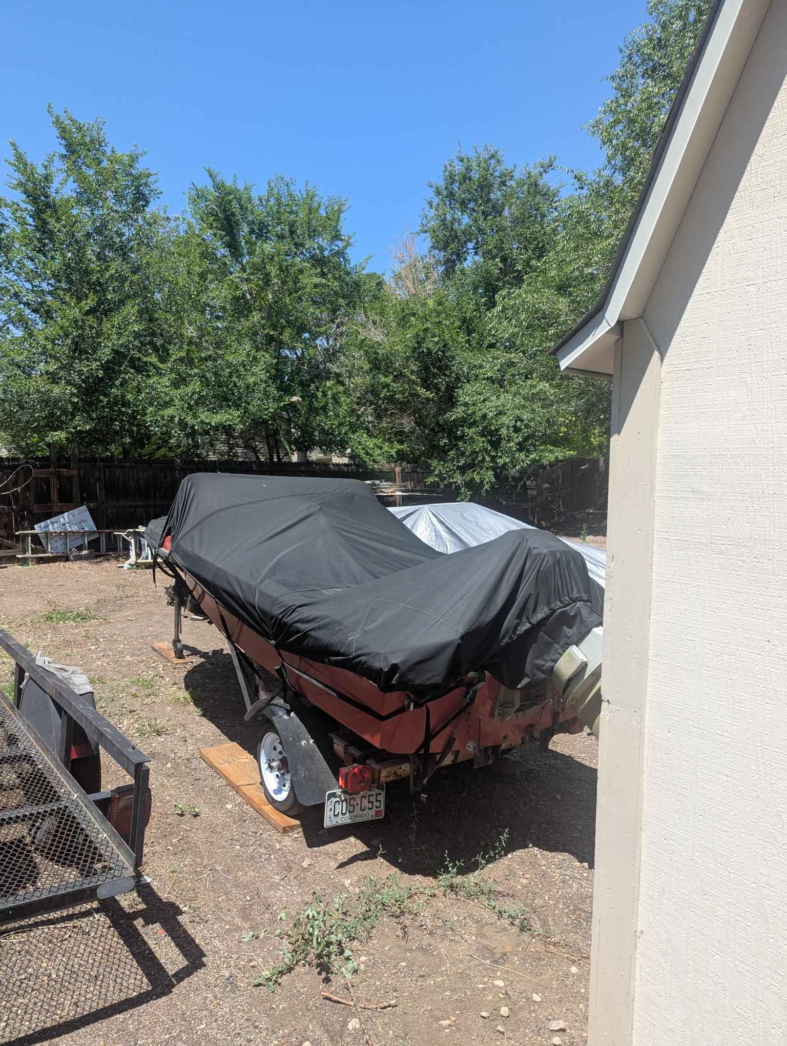 A 1972 14-foot Swiss Craft runabout, covered and parked on a trailer outdoors.