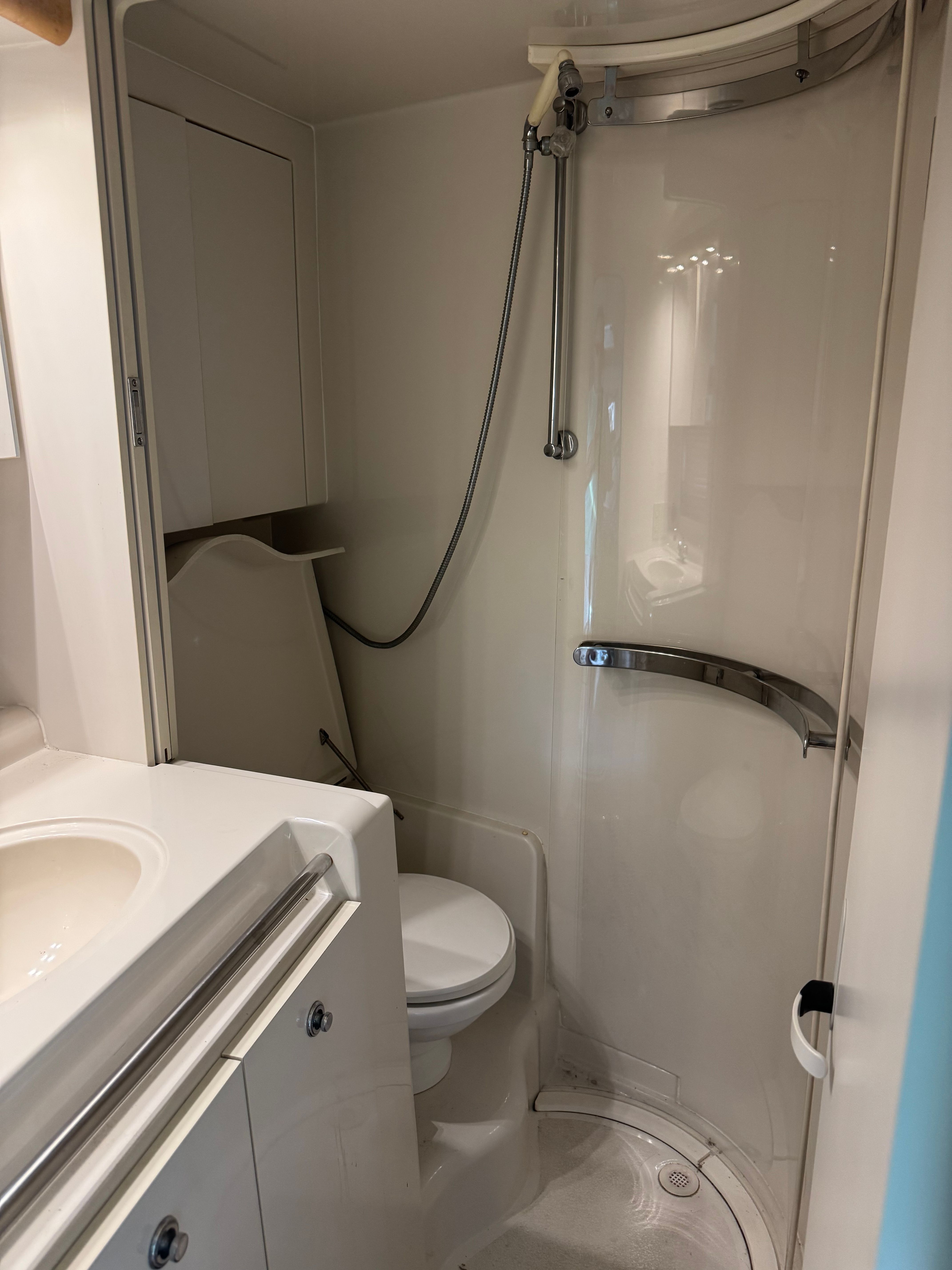 Bathroom with shower, toilet, and sink inside a boat.