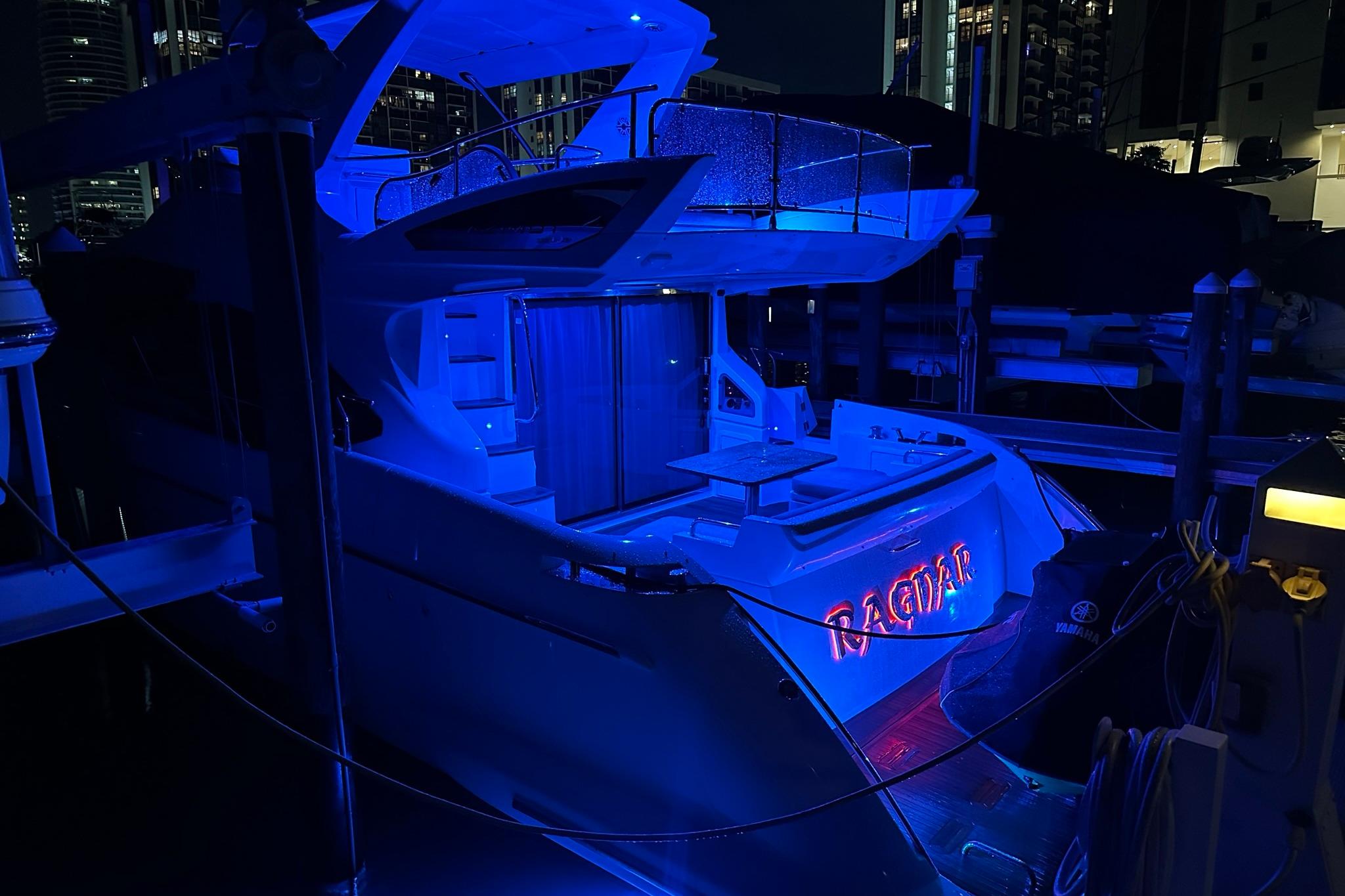 Azimut Fly 53 yacht, 2013 model, illuminated in blue at night, docked in a marina.