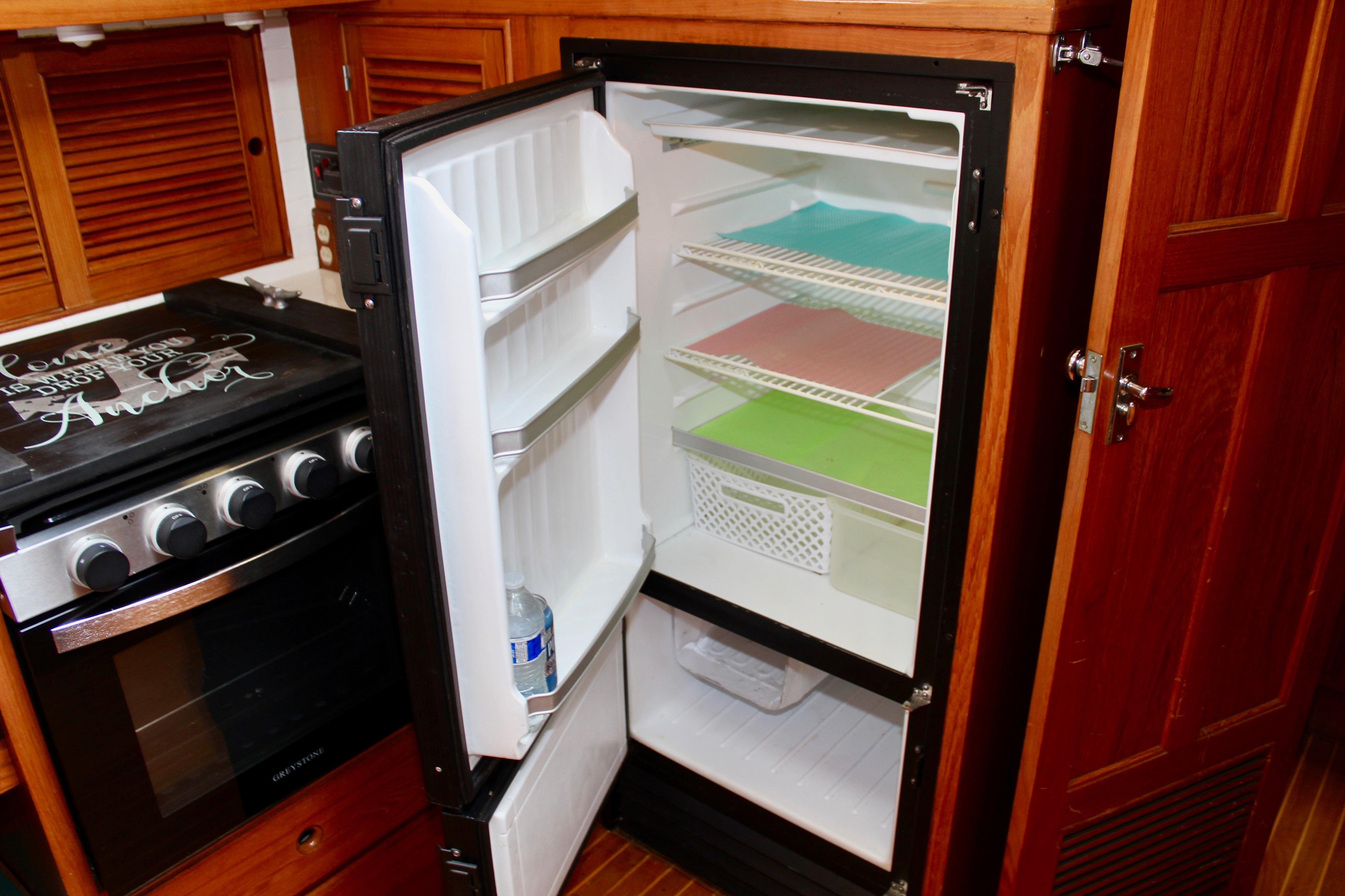 Open refrigerator in 1986 Kha Shing Spindrift 46 yacht kitchen, with colorful shelves.