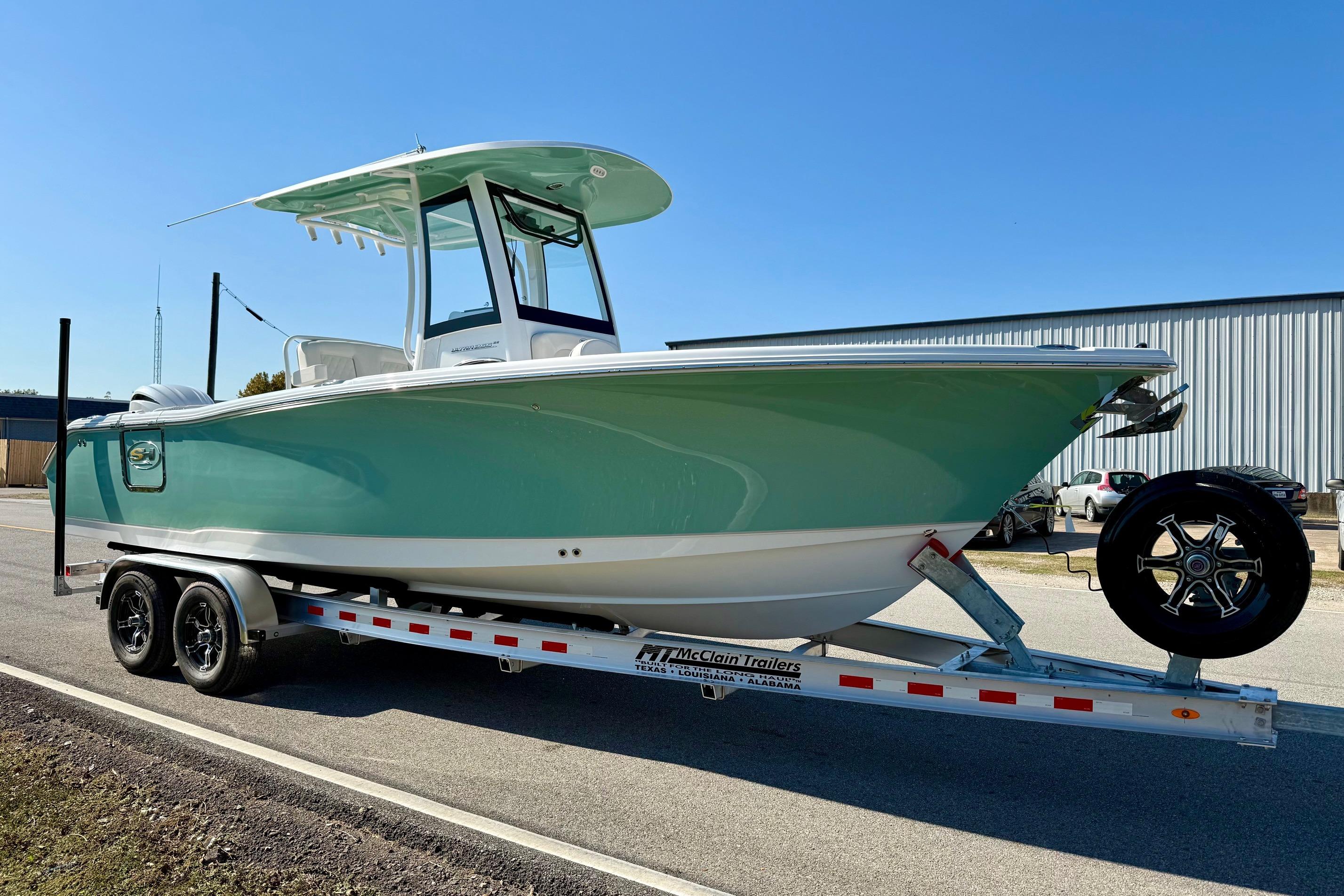 2026 Sea Hunt Ultra 255 SE boat on trailer, parked outdoors under clear blue sky.