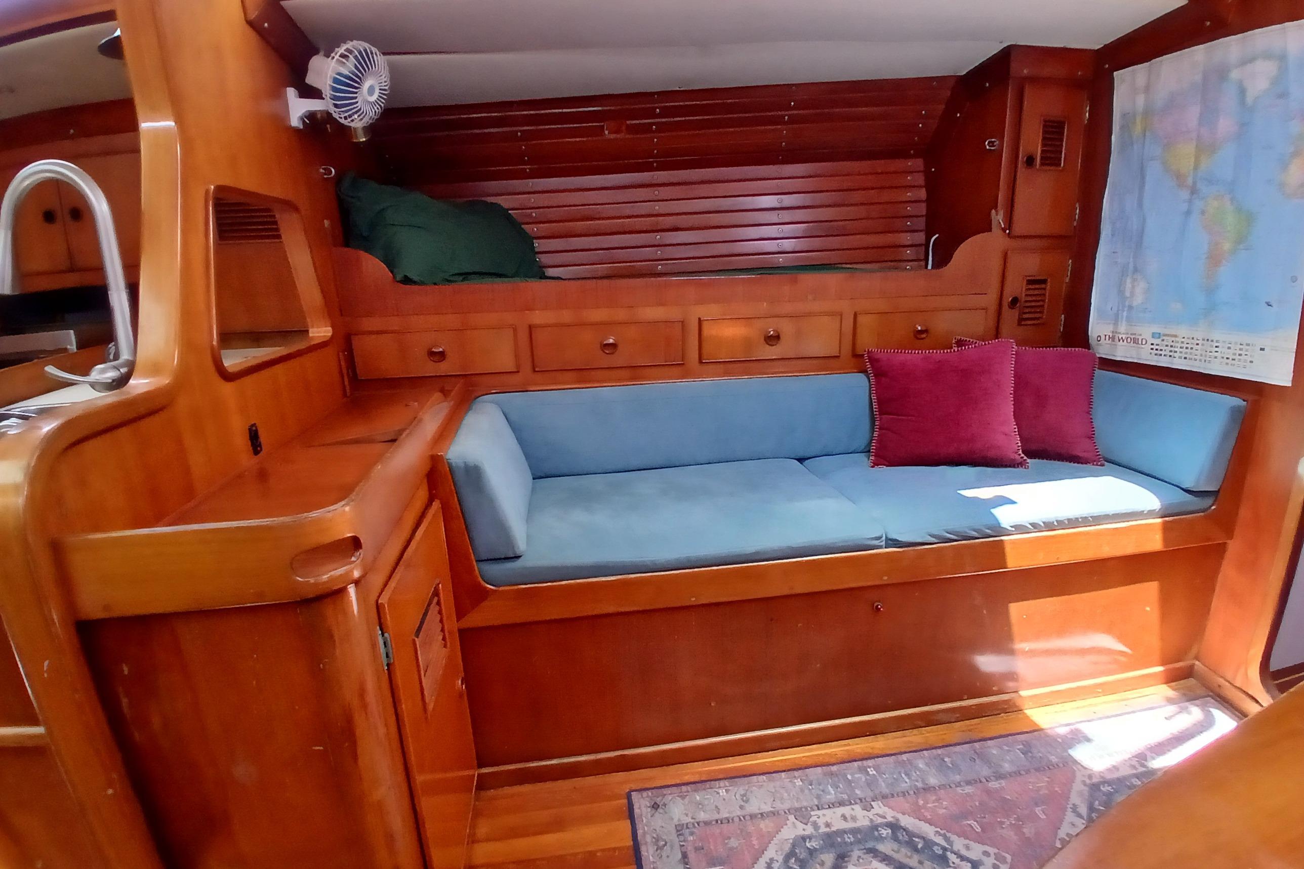 Cozy 1981 SKYE 51 yacht interior with wooden cabinetry, blue seating, and world map.