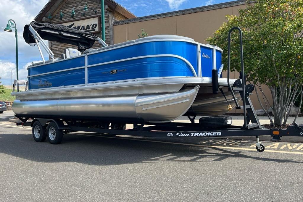 2026 Sun Tracker Party Barge 22 DLX pontoon boat on trailer, parked outdoors.