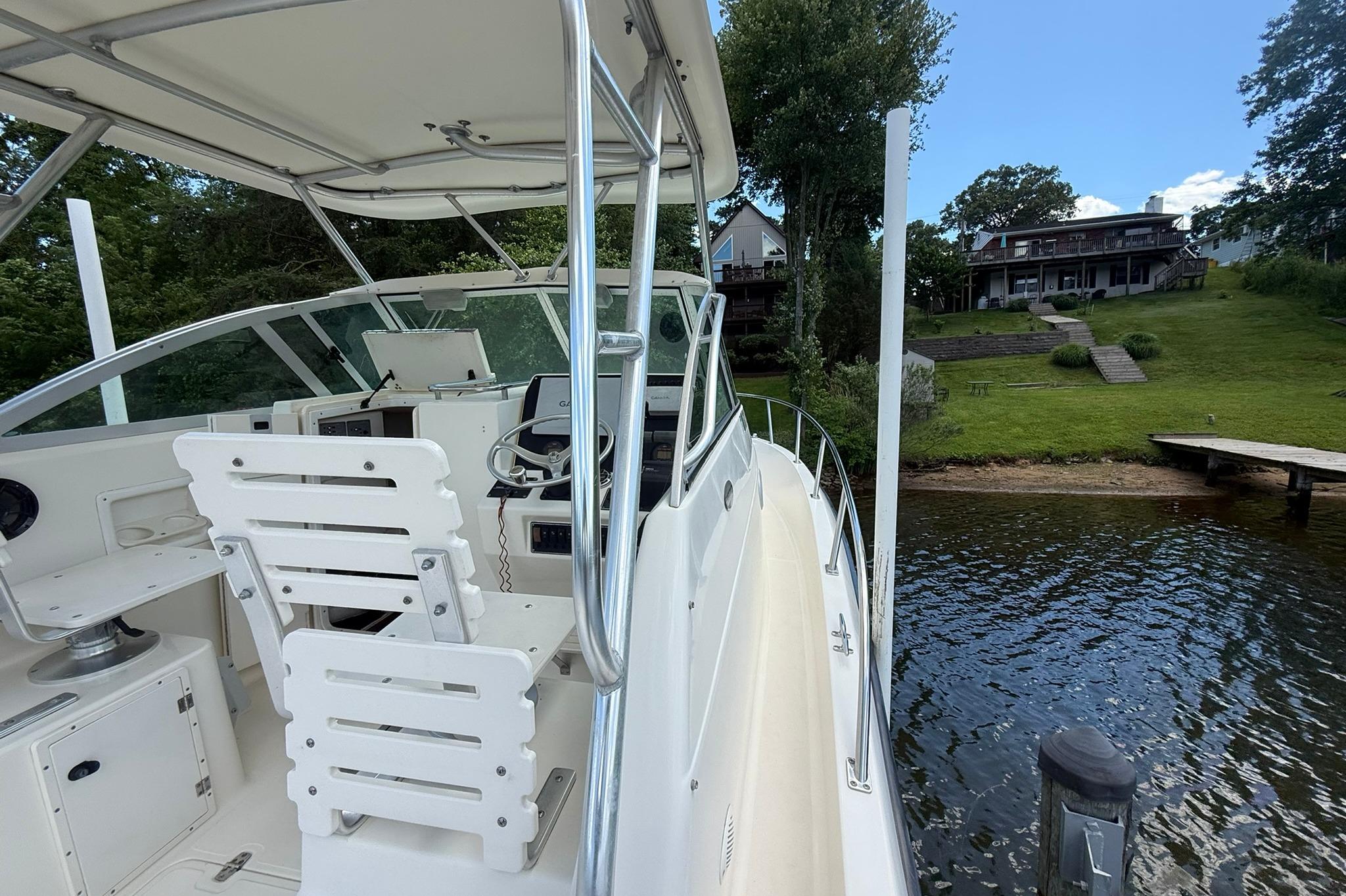 2003 Pursuit 2870 Walkaround boat docked by a lakeside house.