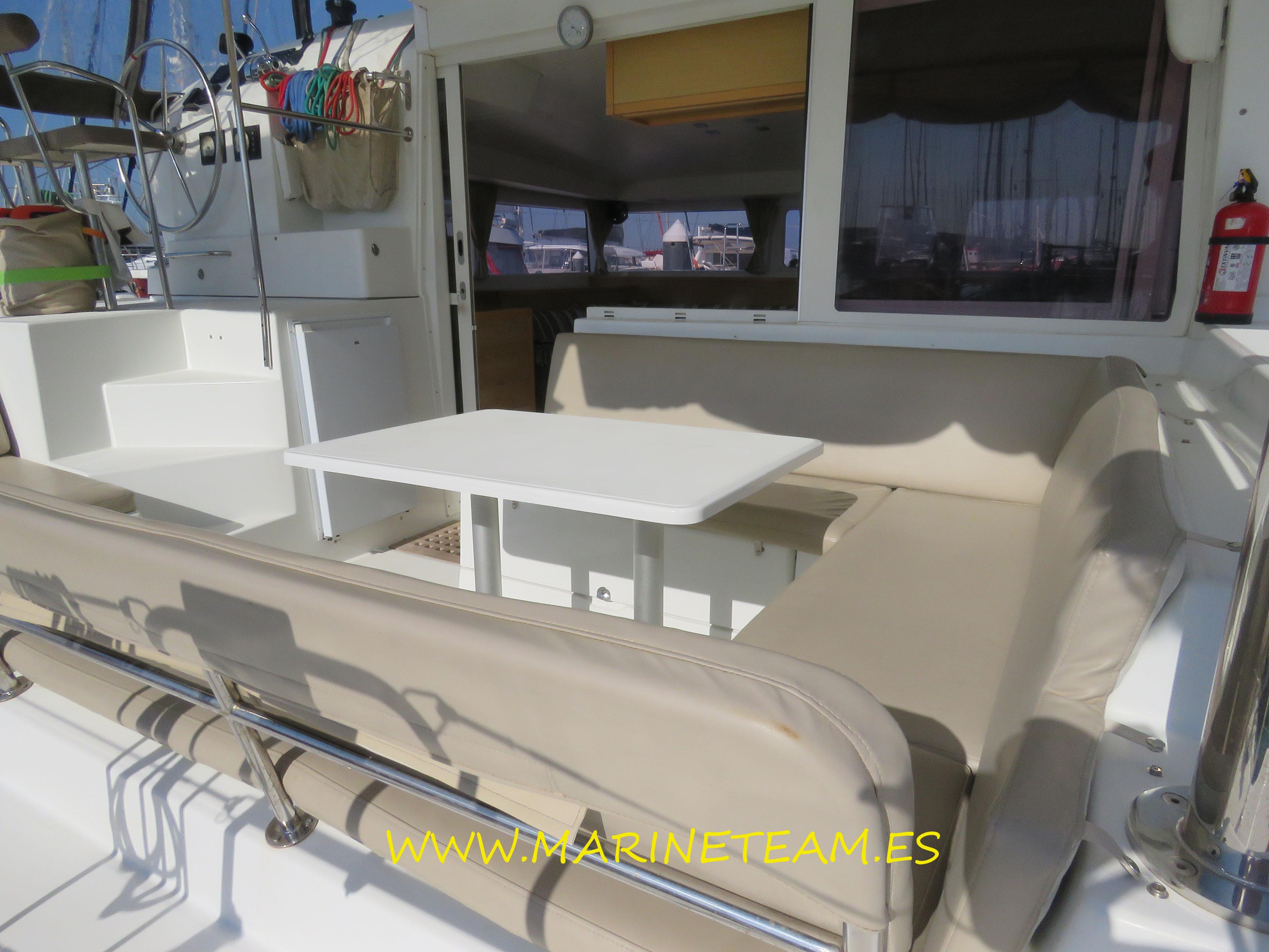 Outdoor seating area on a 2015 Lagoon 400 S2 catamaran with table and cushions.