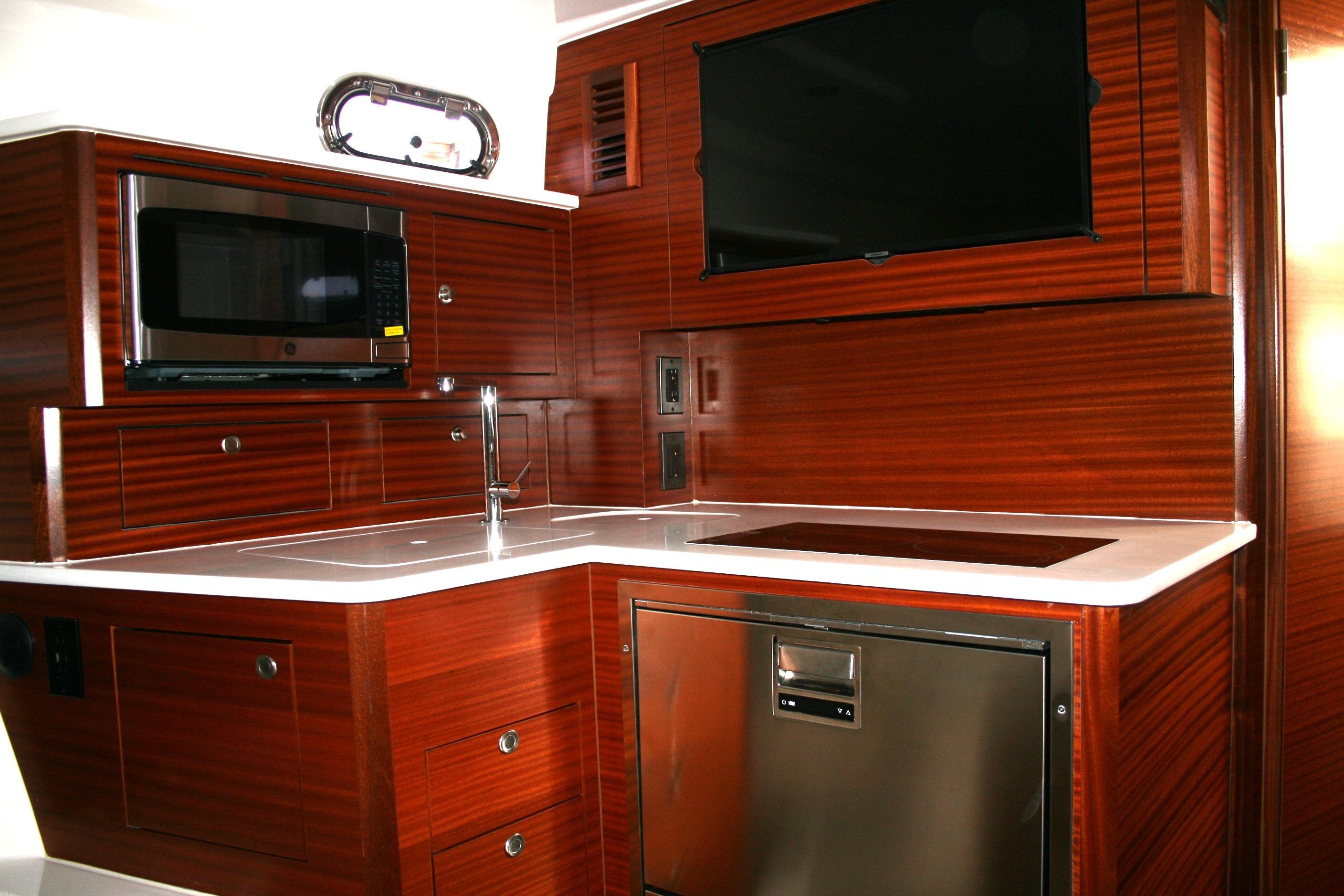 Luxurious 2025 Pursuit OS 405 Offshore yacht kitchen with modern appliances and sleek wood finish.