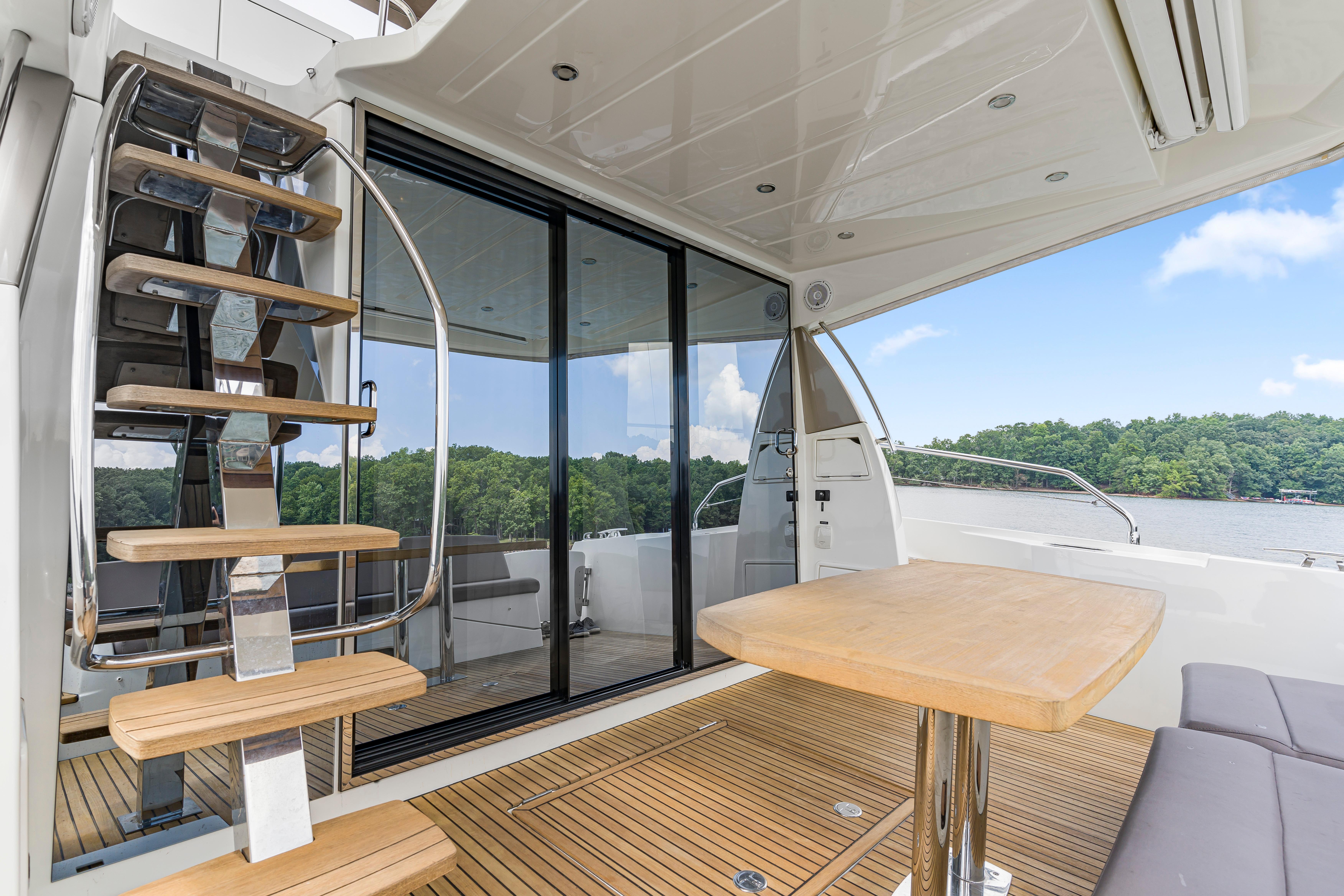 Luxurious 2017 Prestige 500 yacht interior with wooden deck, modern staircase, and scenic water view.