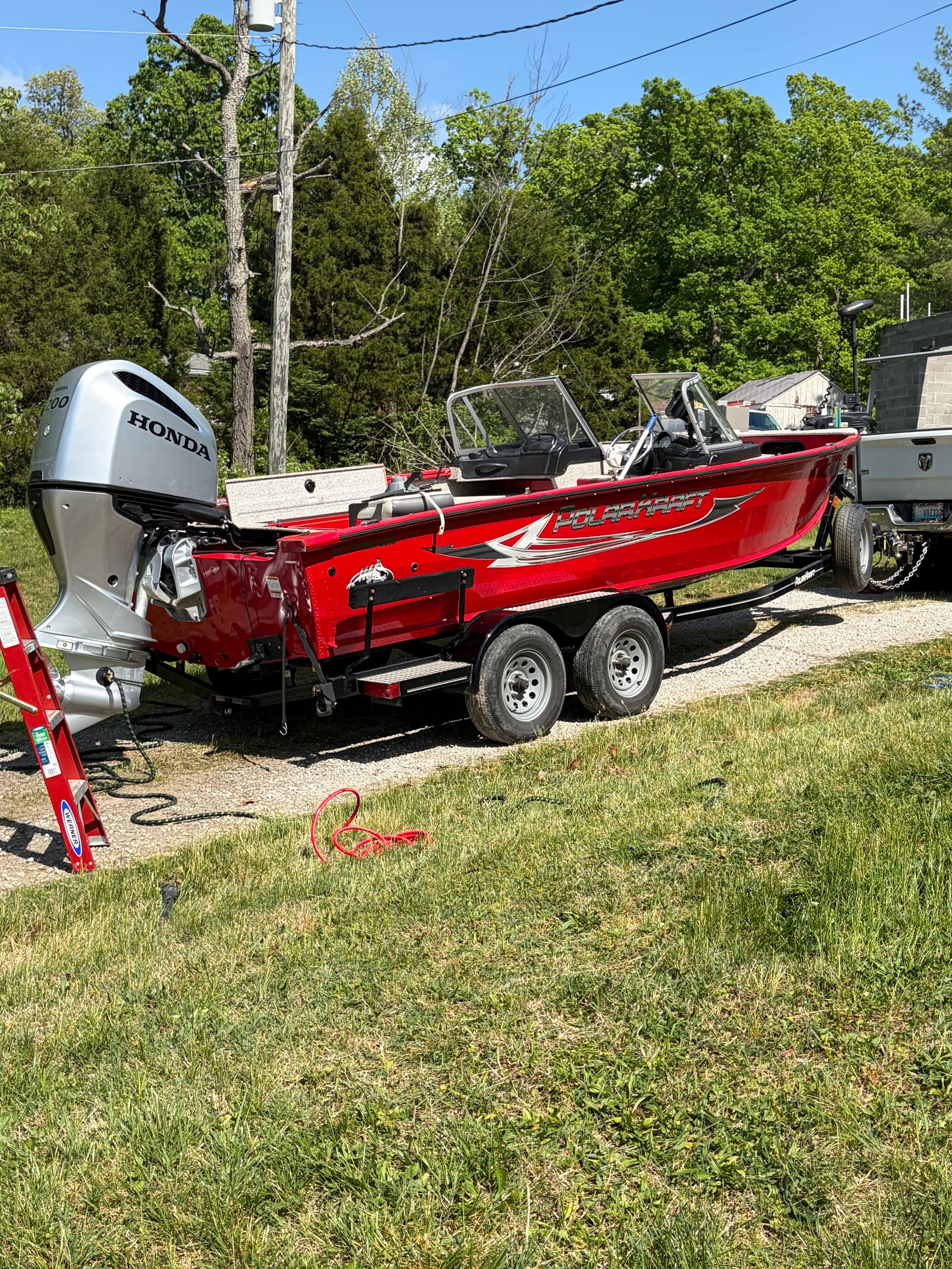Red Polar Kraft Outlander 2010 boat, 2024 model, with Honda engine outdoors.