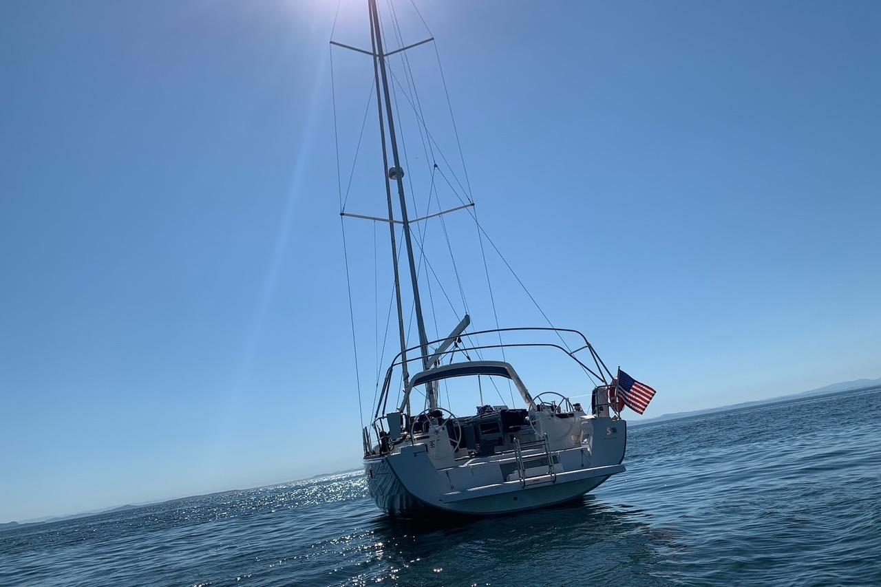 2018 Beneteau Oceanis 45 sailboat on calm sea under clear blue sky.