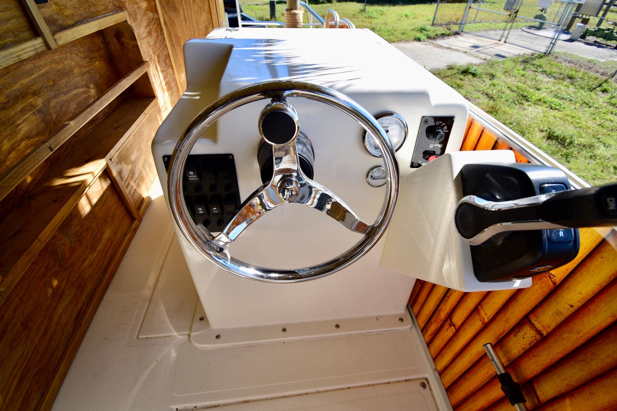 Steering console of 2023 Beachcat 23 Catamaran with chrome wheel and control panel.