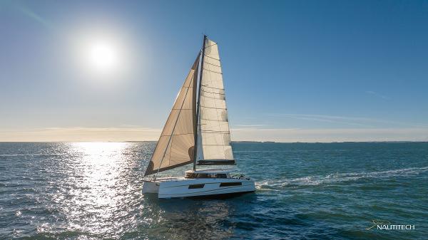 Sailing catamaran Nautitech 48 Open 2025 gliding on sunlit ocean waters.