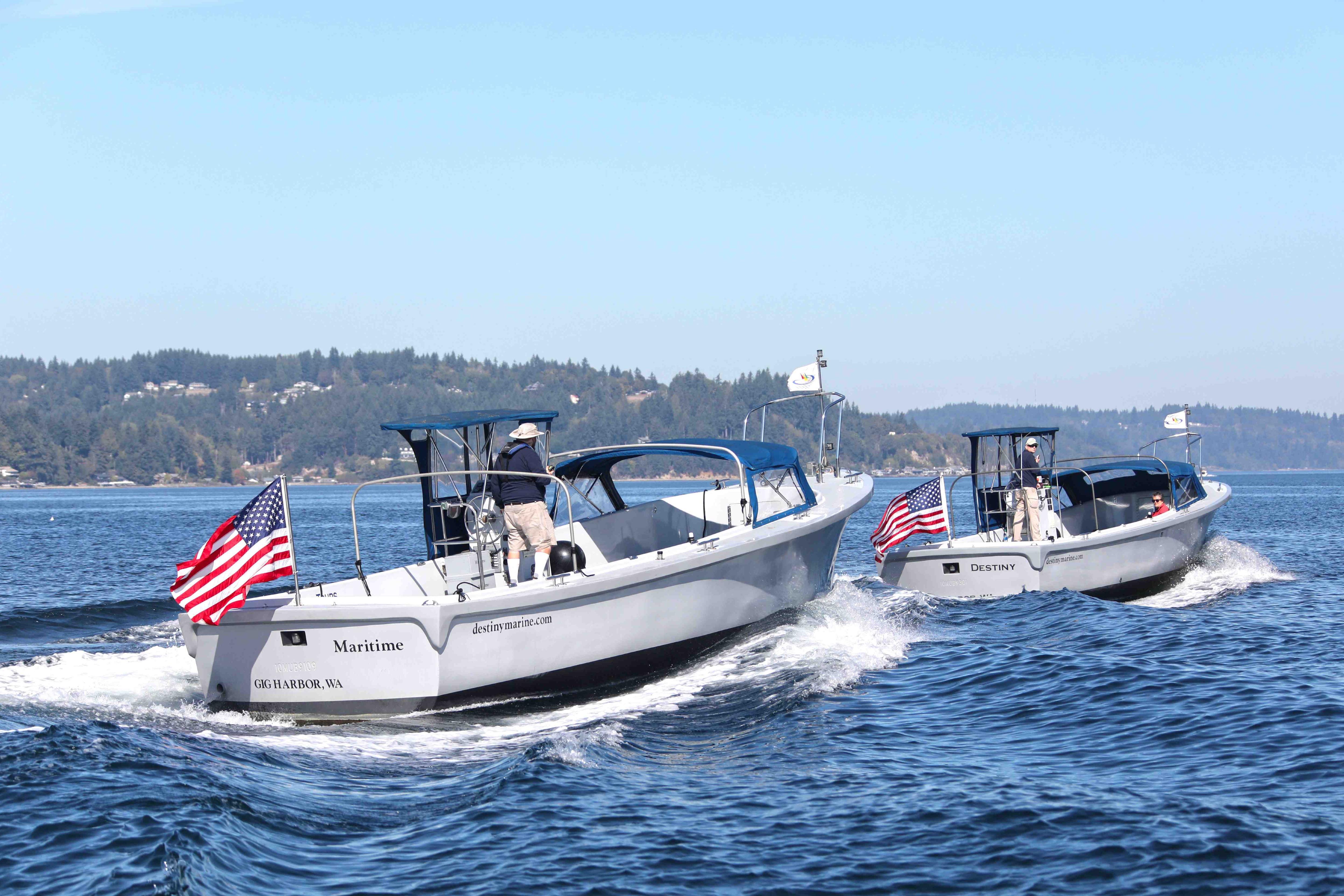 Two Navy Lodge boats with American flags cruising on a scenic waterway.