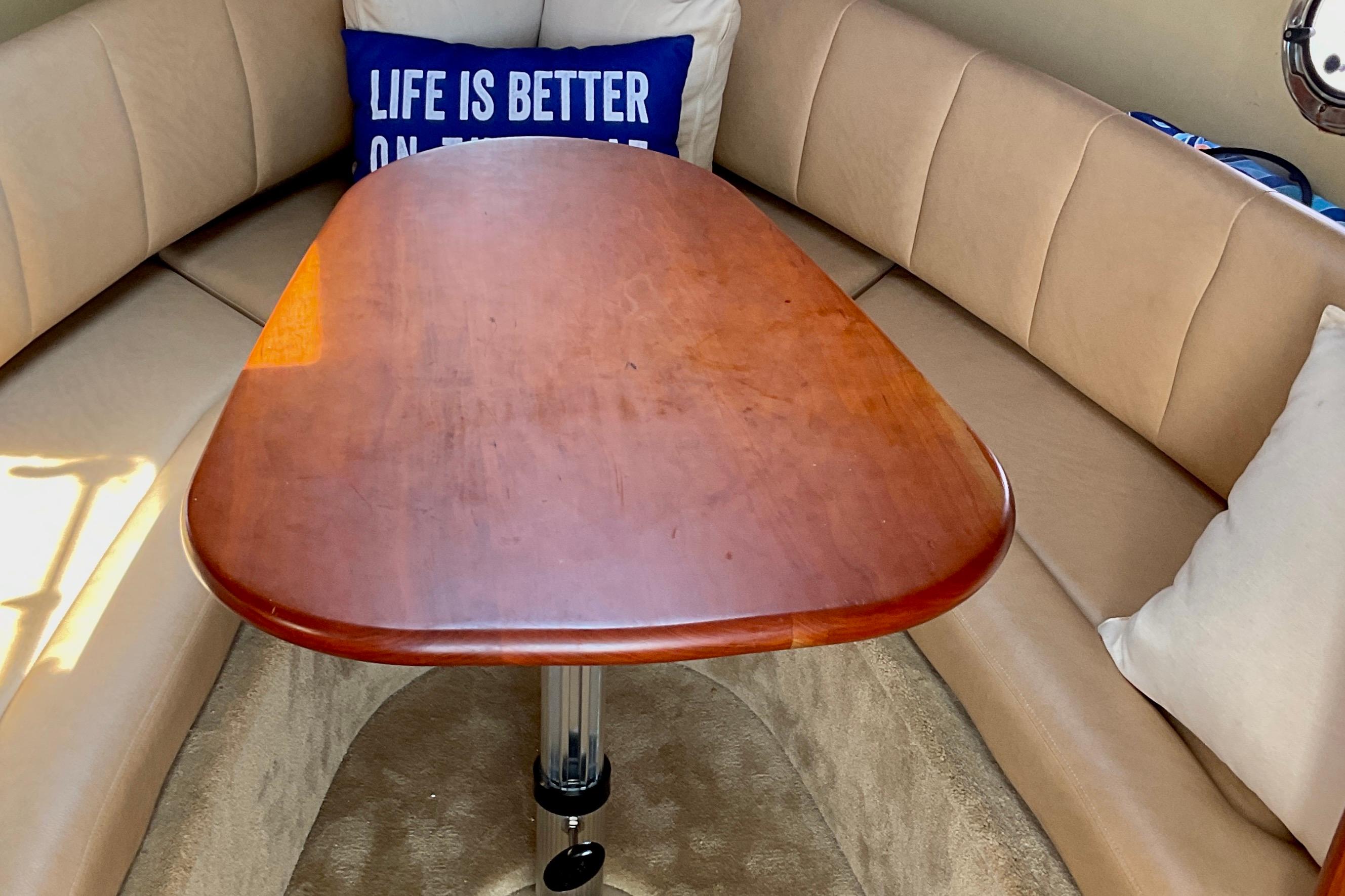 Interior of 2013 Rinker 290 Express Cruiser with wooden table and cushioned seating.