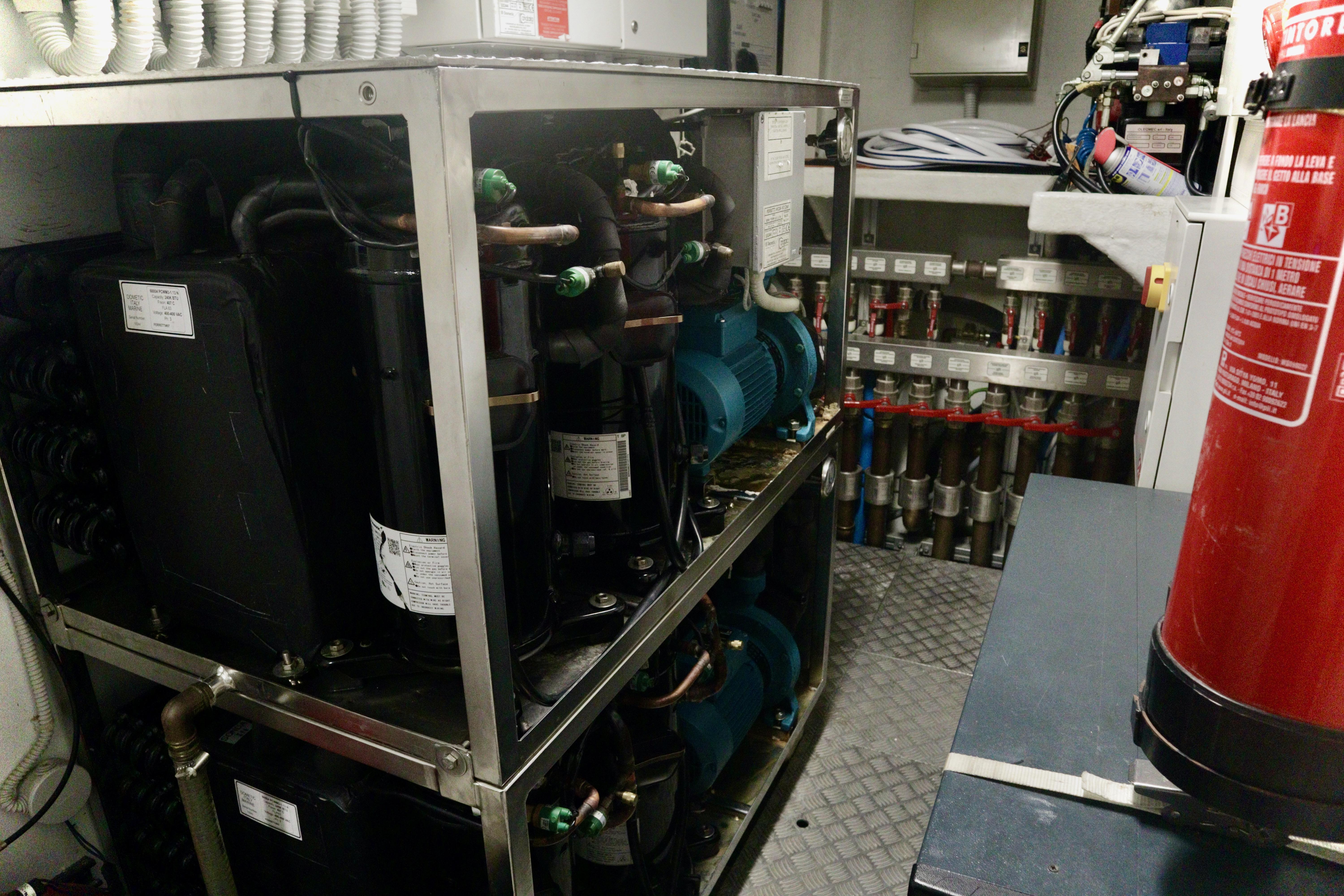 Engine room of 2016 Custom Line 97 yacht with machinery and fire extinguisher.