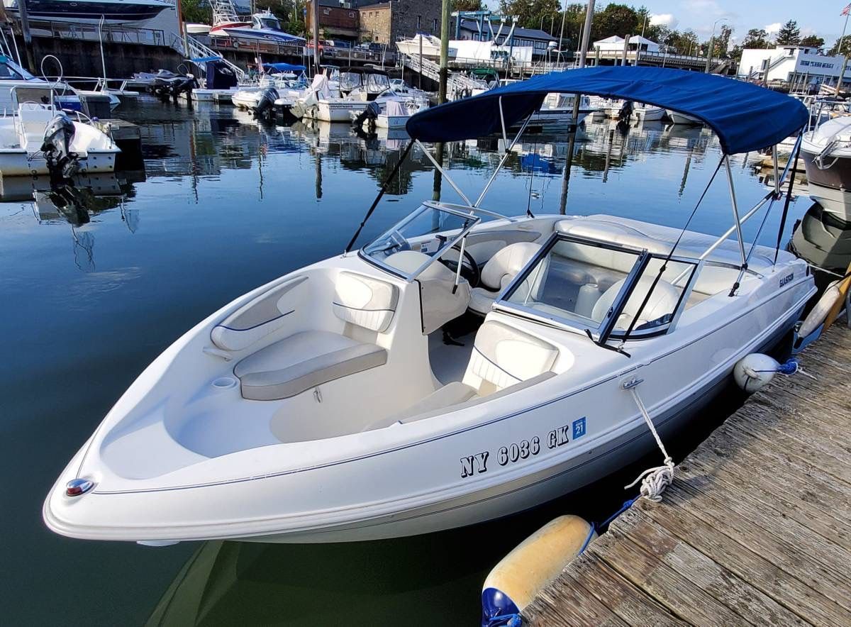 A white 2006 Glastron MX-195 boat docked in a busy harbor.