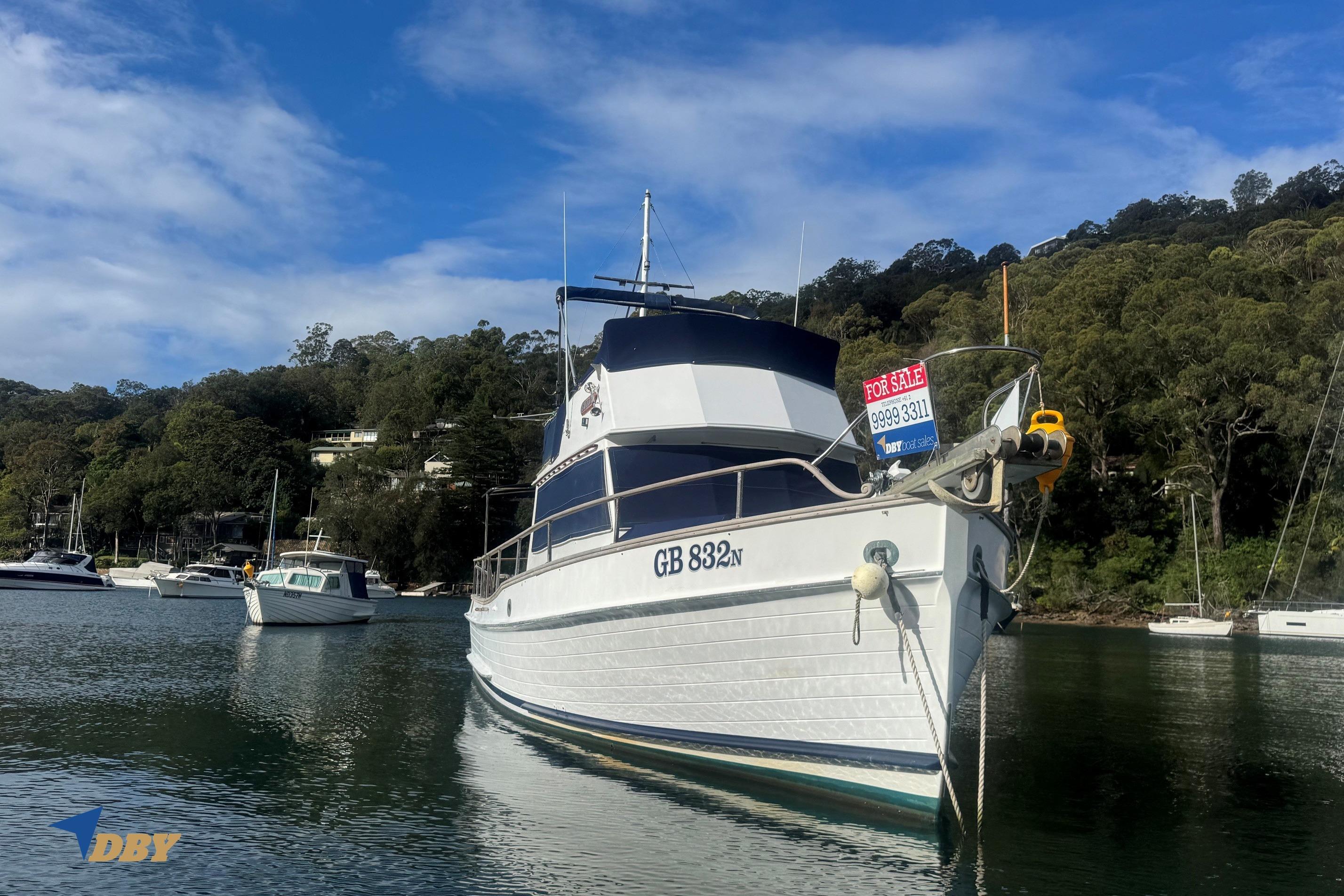 1980 Grand Banks 32 Sedan boat for sale, moored in a scenic harbor setting.