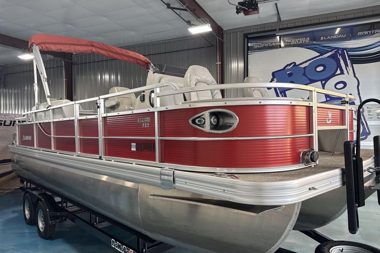 2022 Landau ALURE 232 pontoon boat with red exterior, displayed indoors on a trailer.