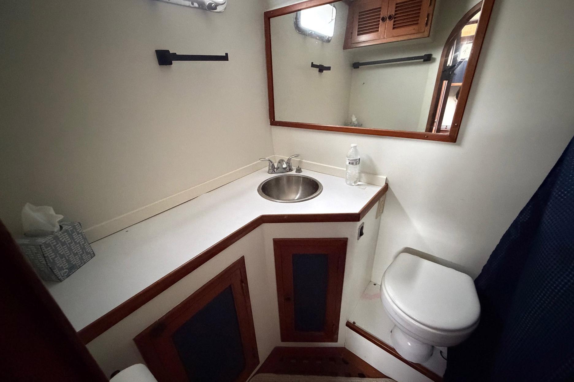 Bathroom interior of 1984 Golden Star 38 Trawler with sink, mirror, and toilet.
