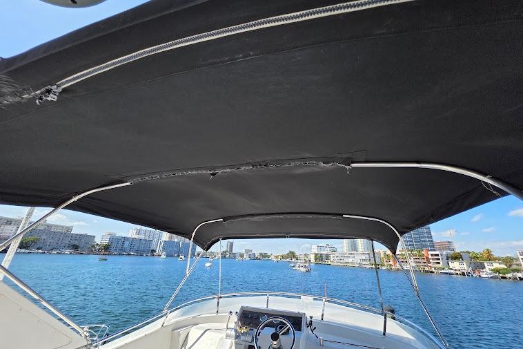1993 McKinna 48 Pilothouse boat with black canopy, overlooking a scenic waterfront cityscape.