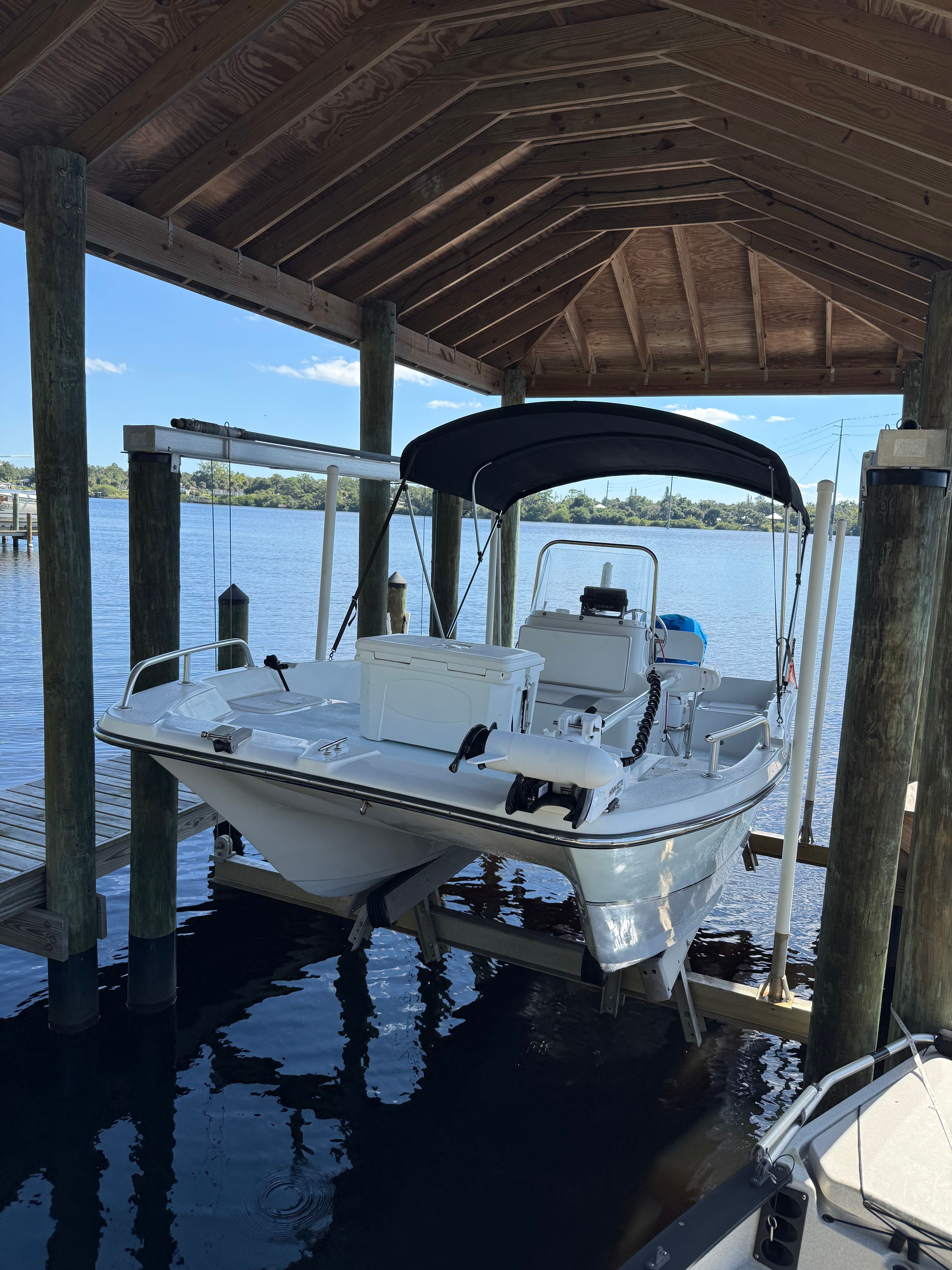 A 2011 Carolina Cat 18CC boat is suspended in a covered boat lift over the water.