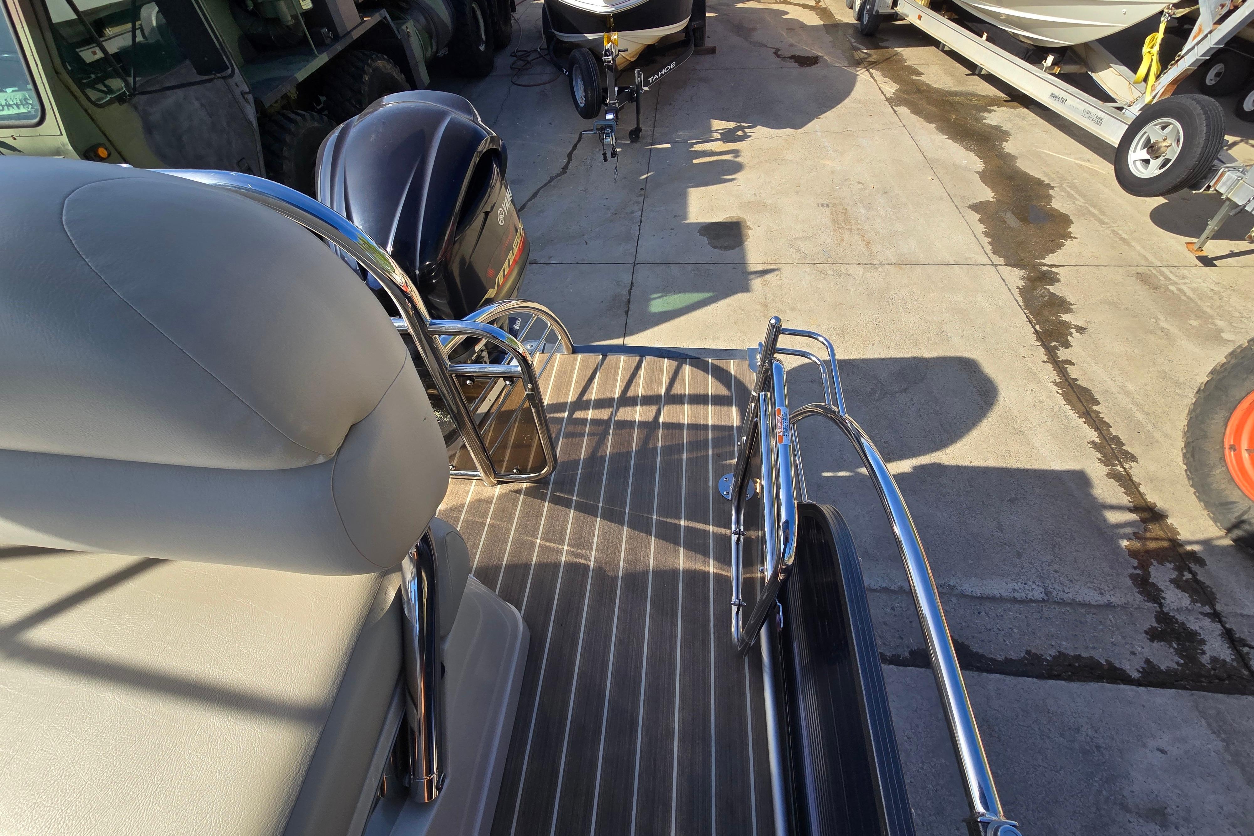 2015 Manitou 25 SES boat interior with seating and railing, parked on concrete.