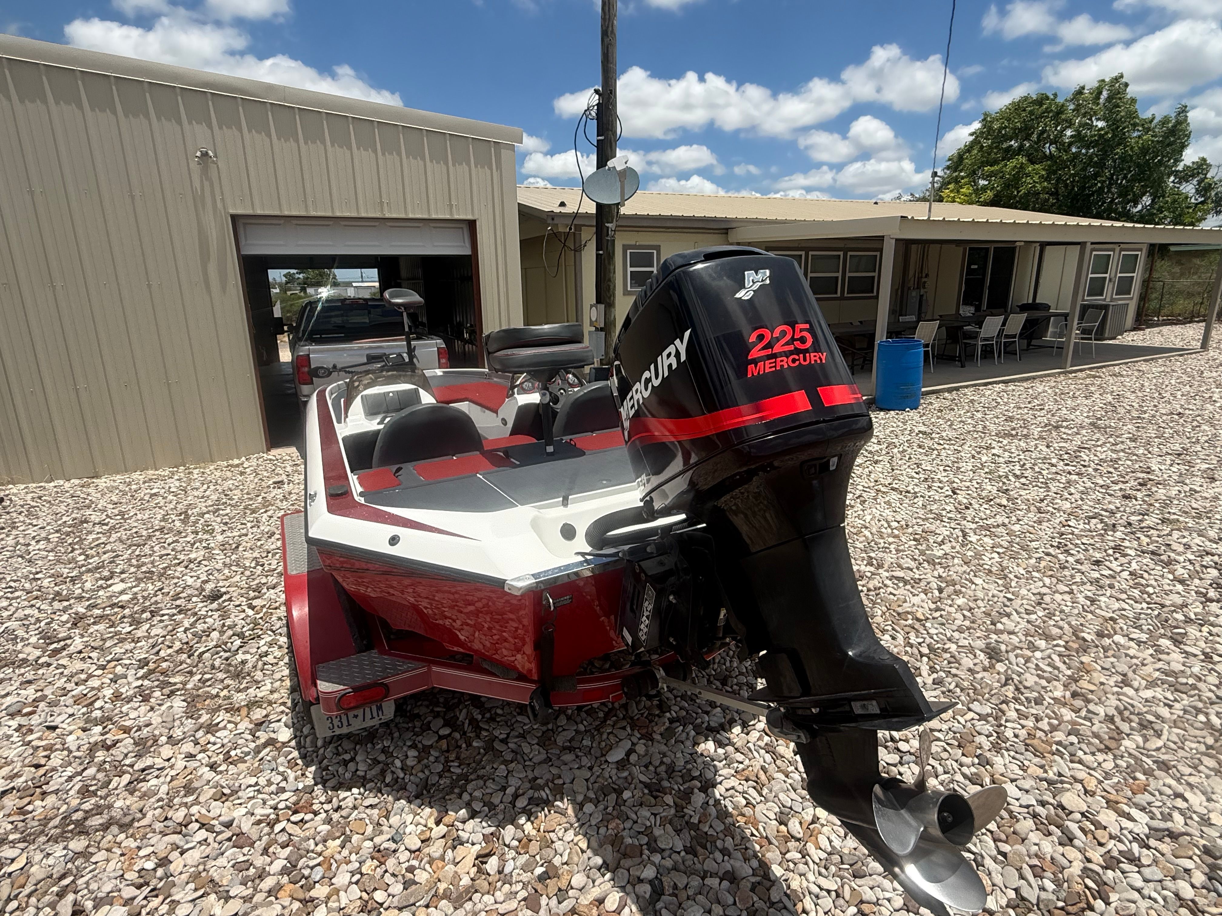 A red 1999 Champion 202 boat with a Mercury 225 engine, parked on a gravel lot.