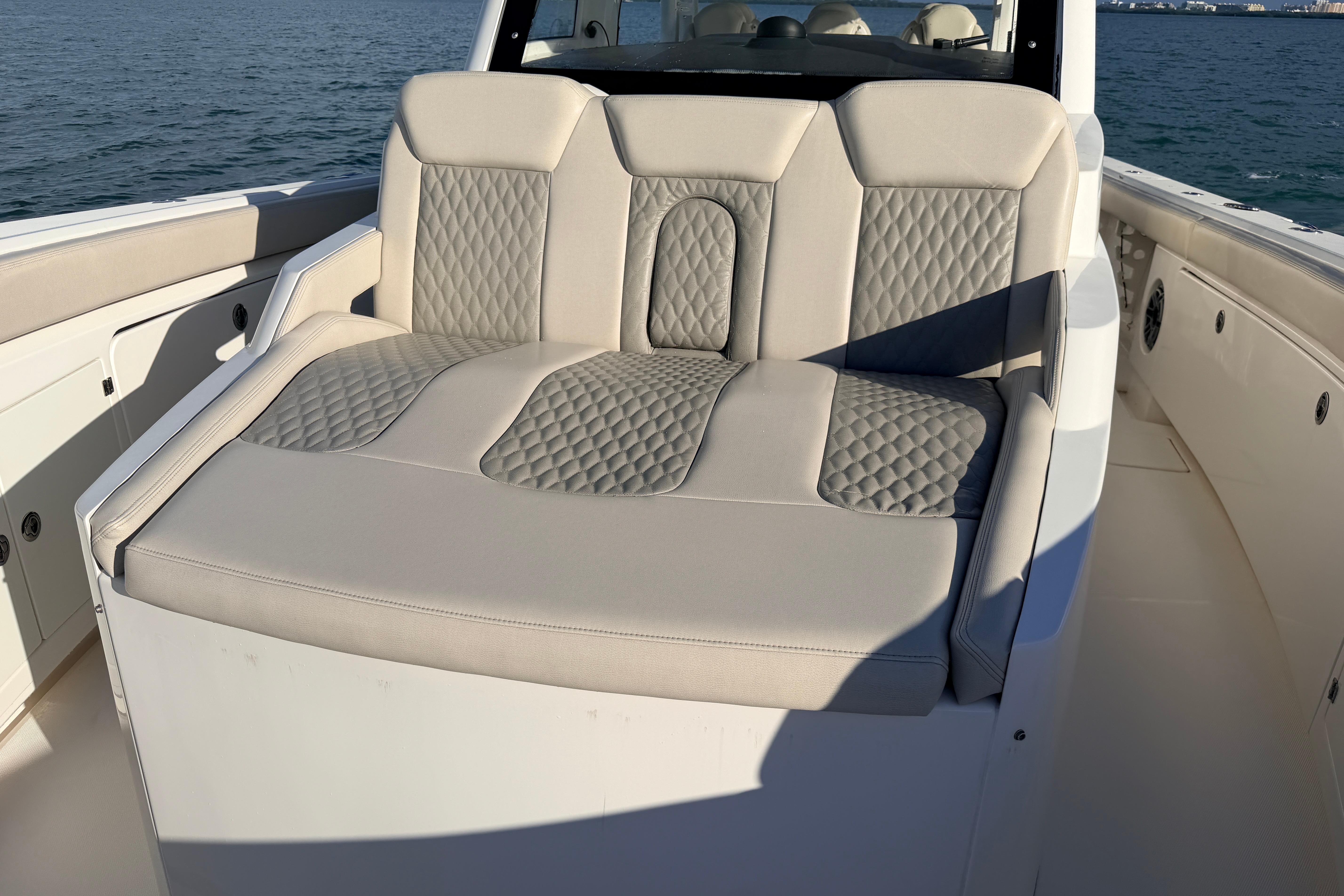 Luxurious seating on 2024 Solace 41 CS boat, featuring quilted upholstery and ocean backdrop.