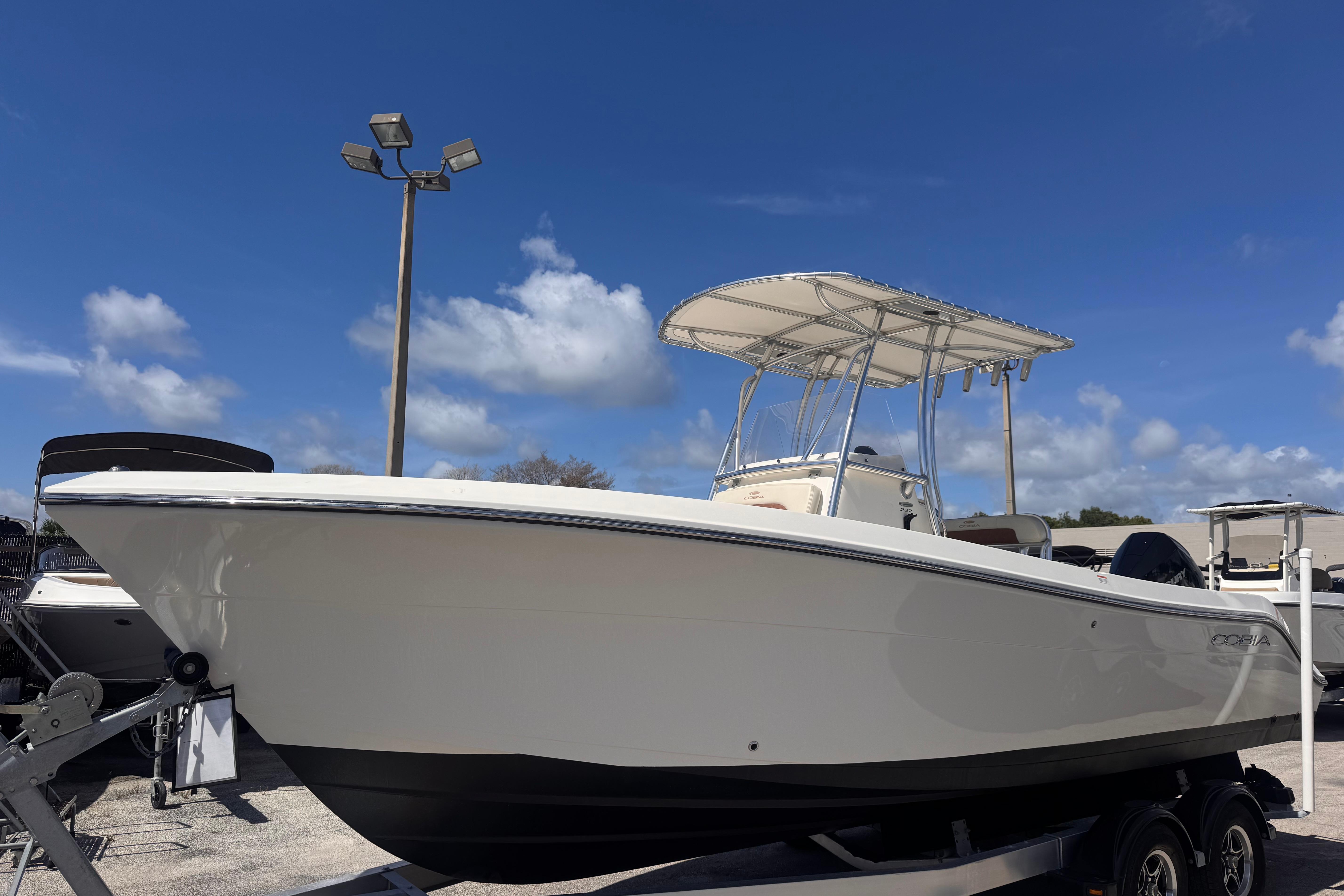2023 Cobia 237 Center Console boat on trailer under clear blue sky.