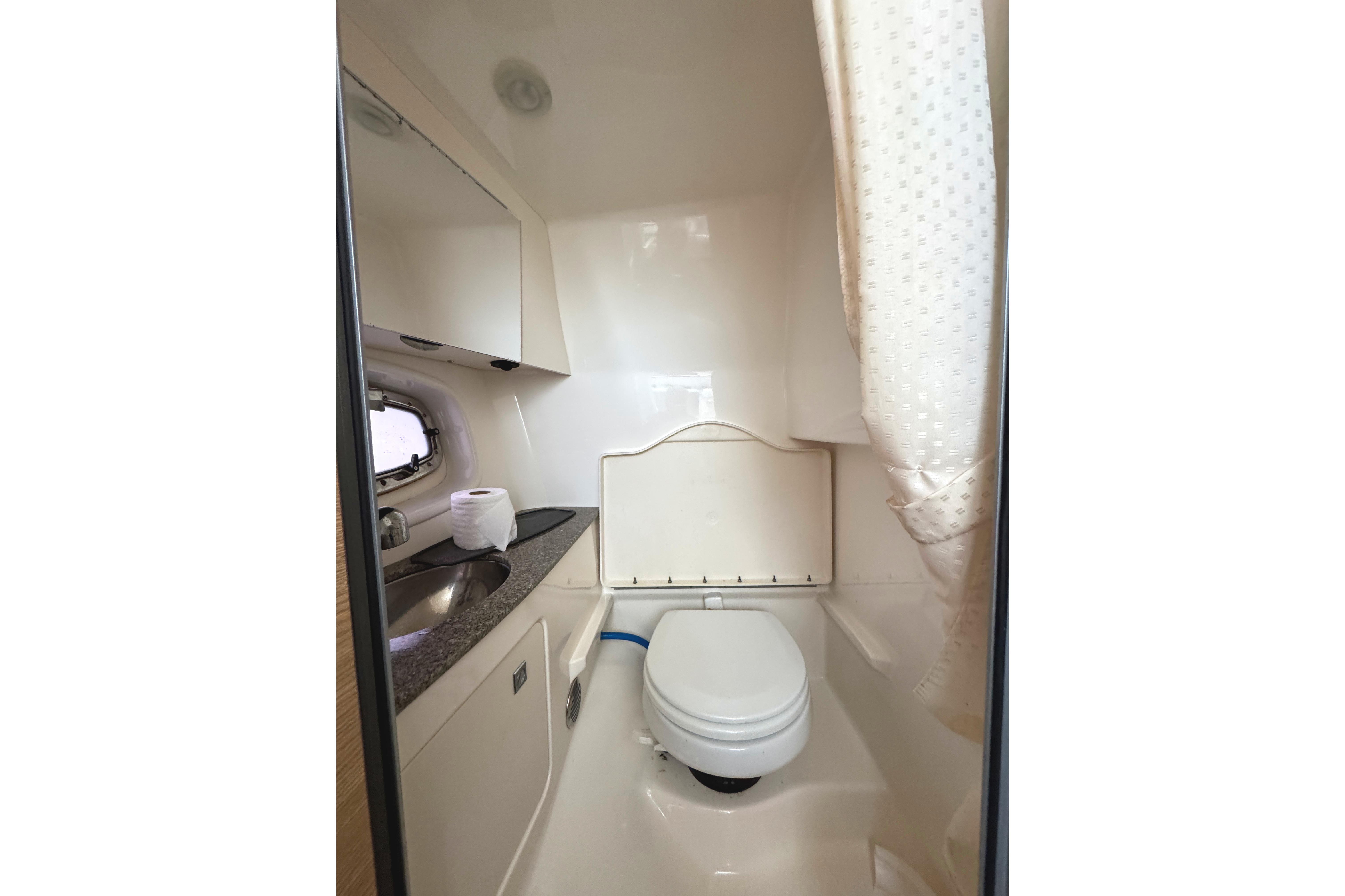 2012 Chaparral 327 SSX boat bathroom with toilet, sink, and window.
