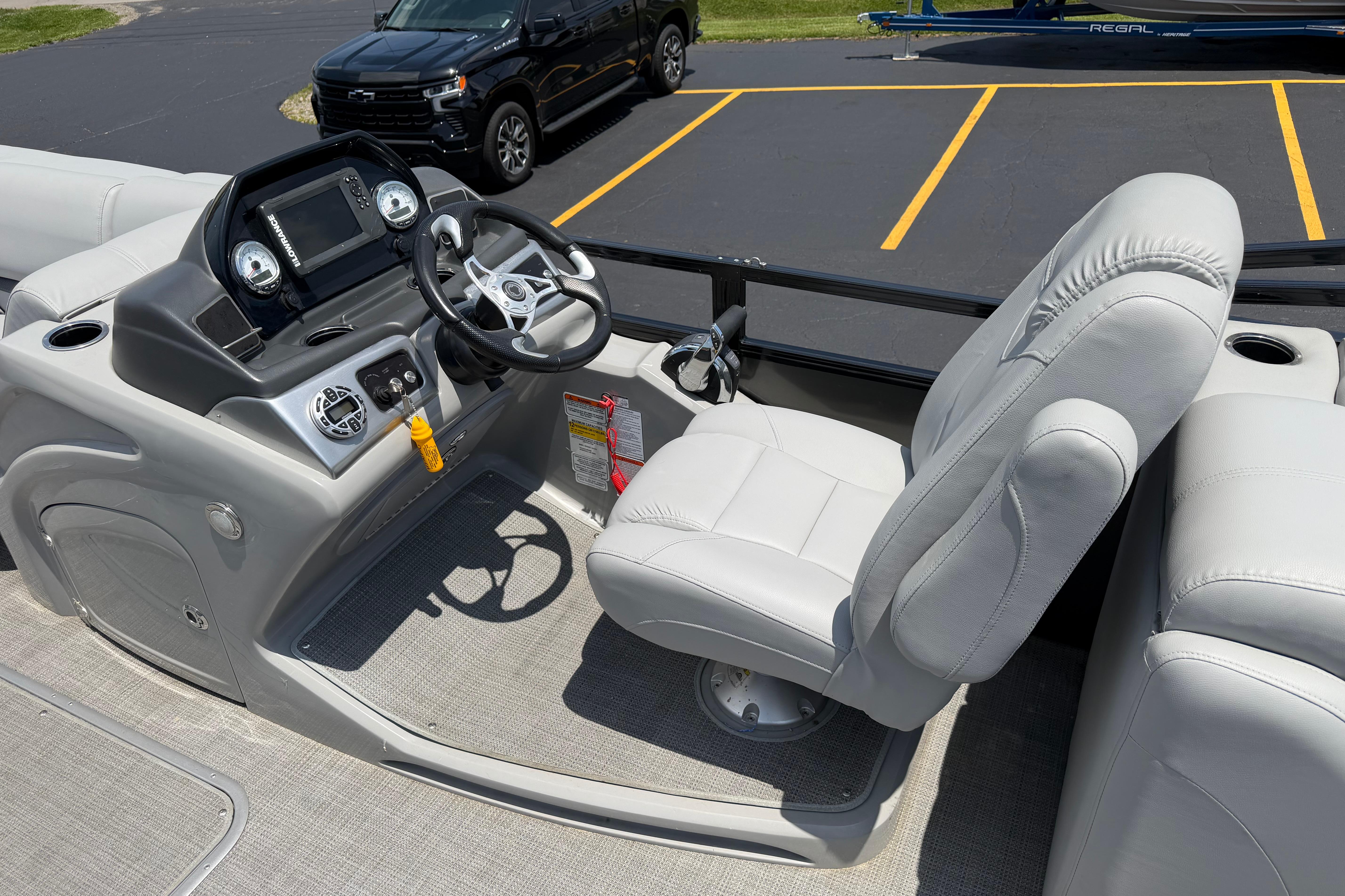 2019 Regency 230 DL3 boat helm with steering wheel and comfortable captain's chair.
