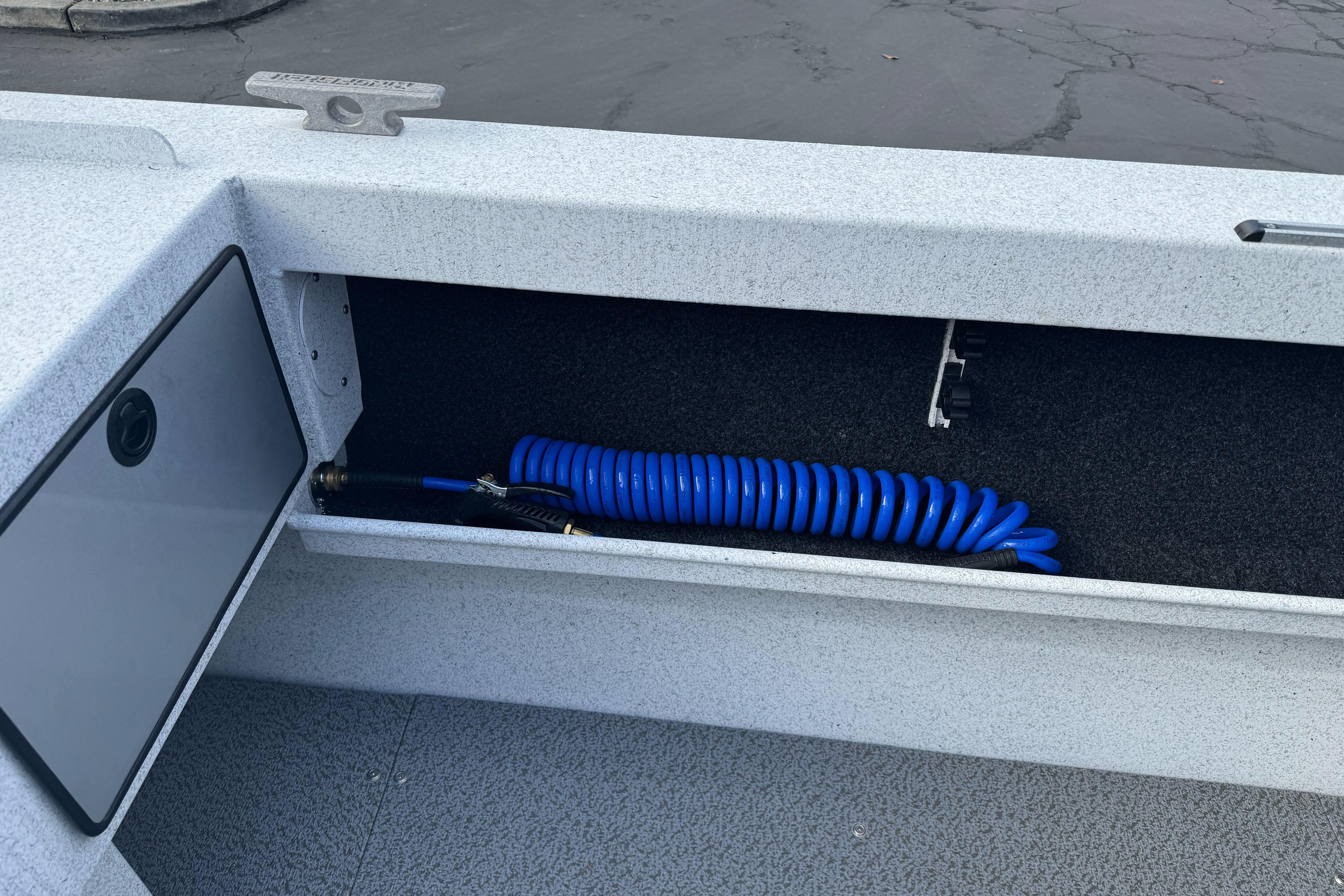 Storage compartment in 2026 KingFisher 2025 Escape boat with coiled blue hose.
