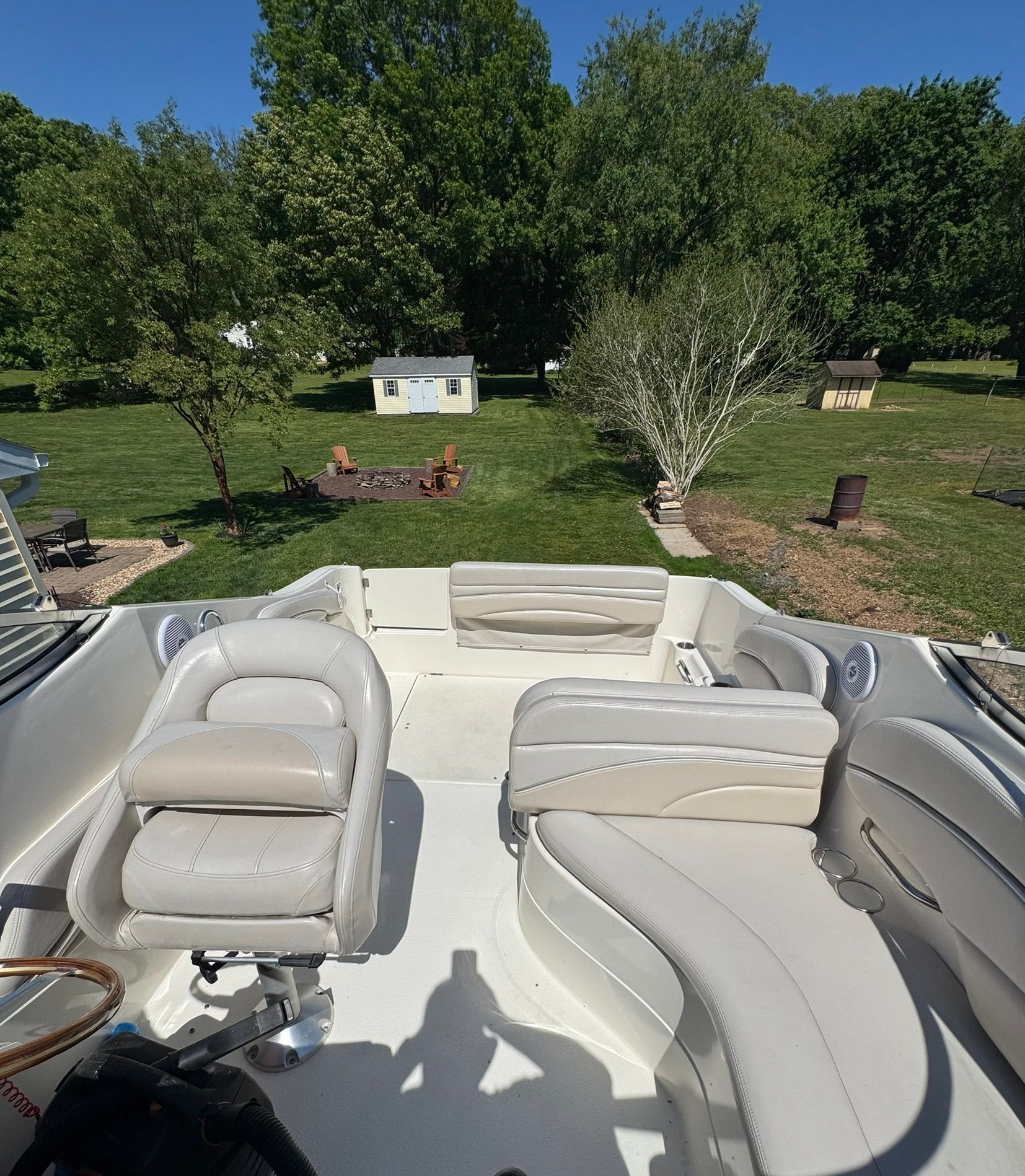 The boat has white leather seats and is on a trailer in a backyard.