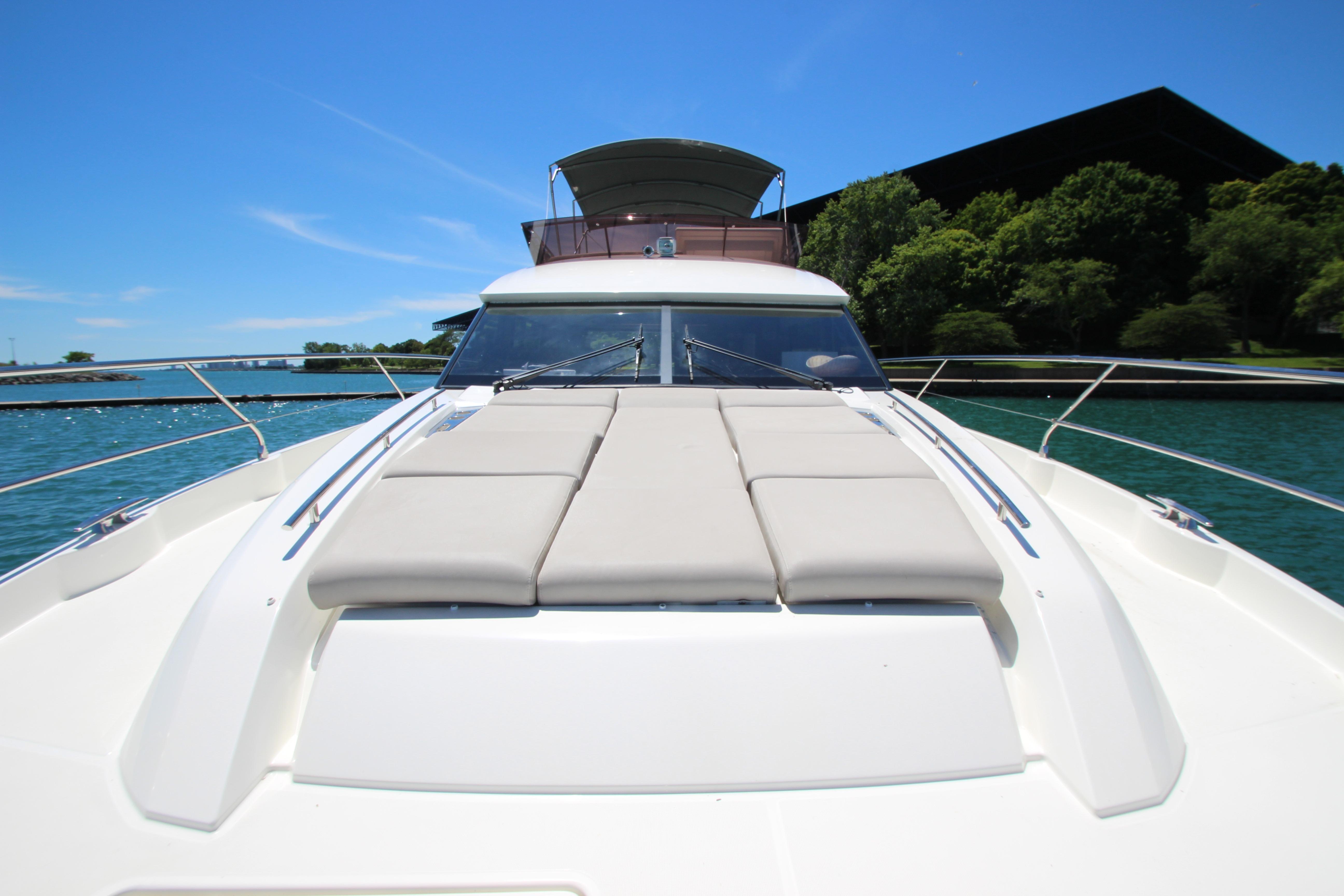 Luxurious 2022 Prestige 520 yacht on serene water, featuring spacious sunbathing deck.