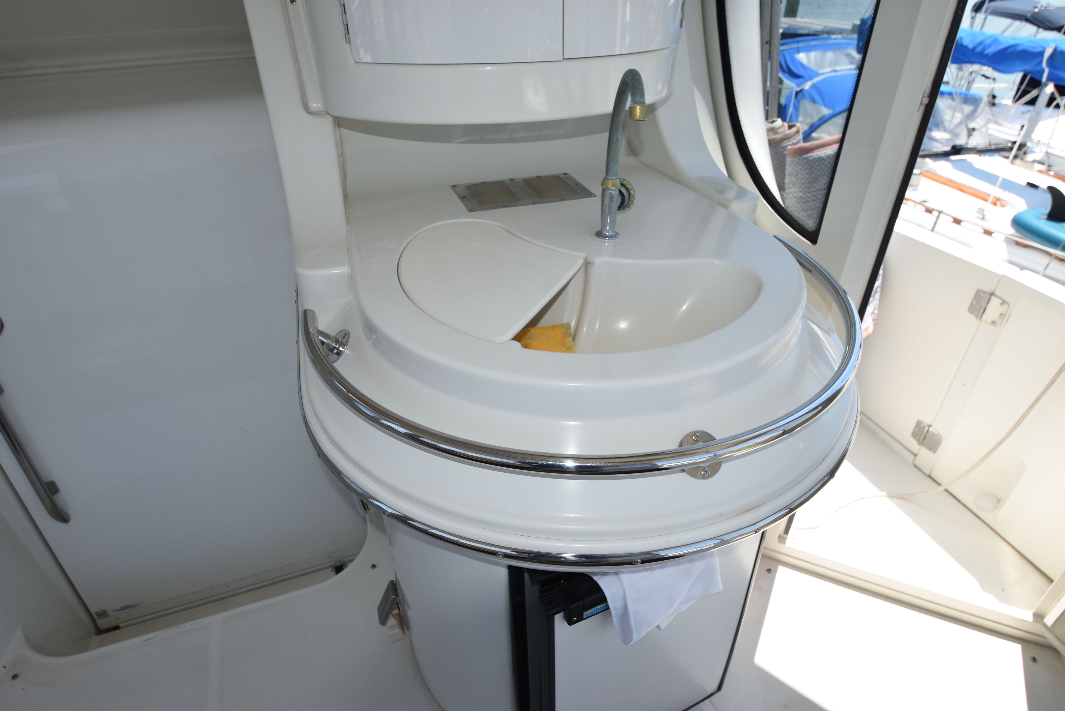 A sleek sink with a faucet on a yacht, surrounded by white surfaces.