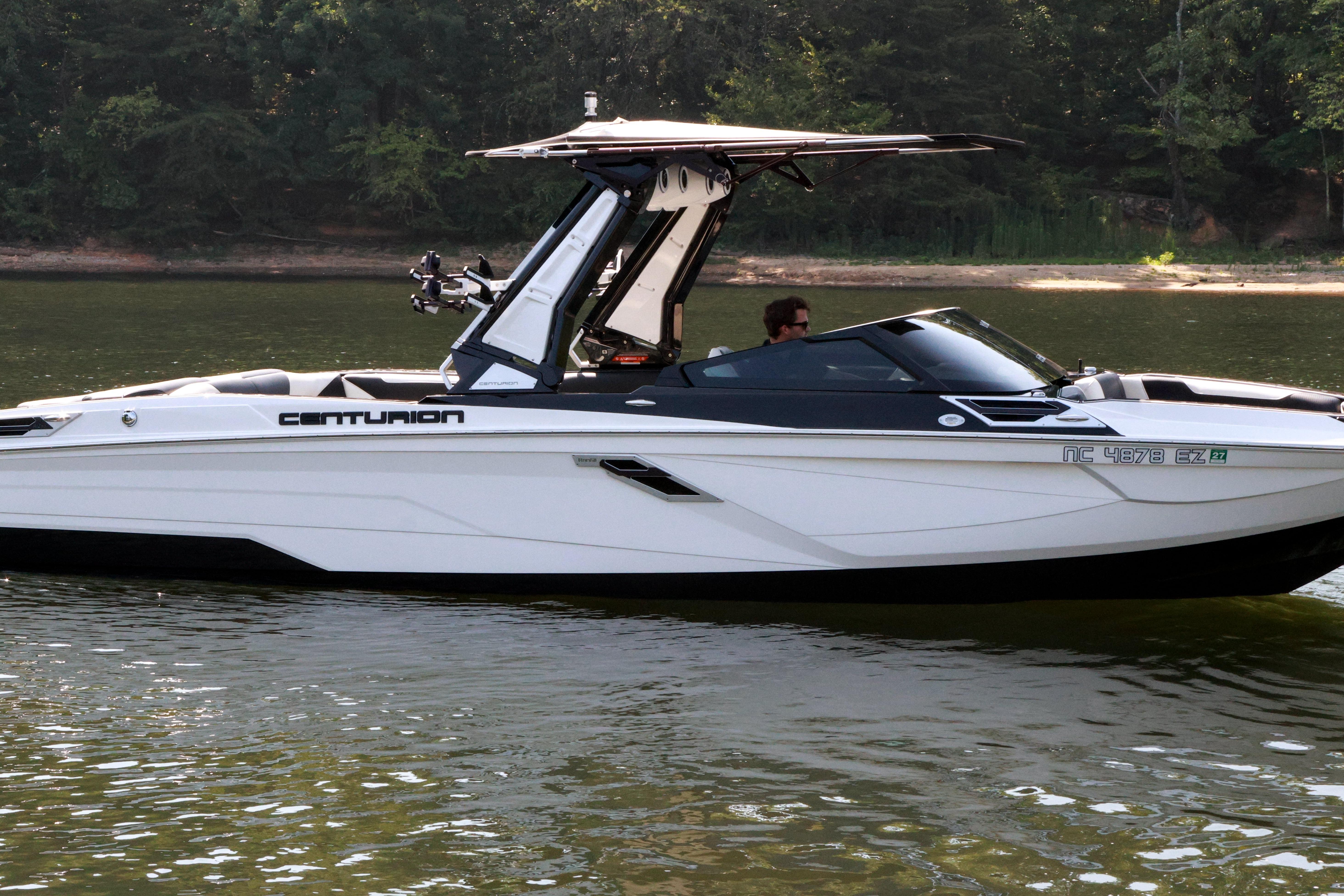2022 Centurion Ri265 boat cruising on a calm lake with lush forest background.