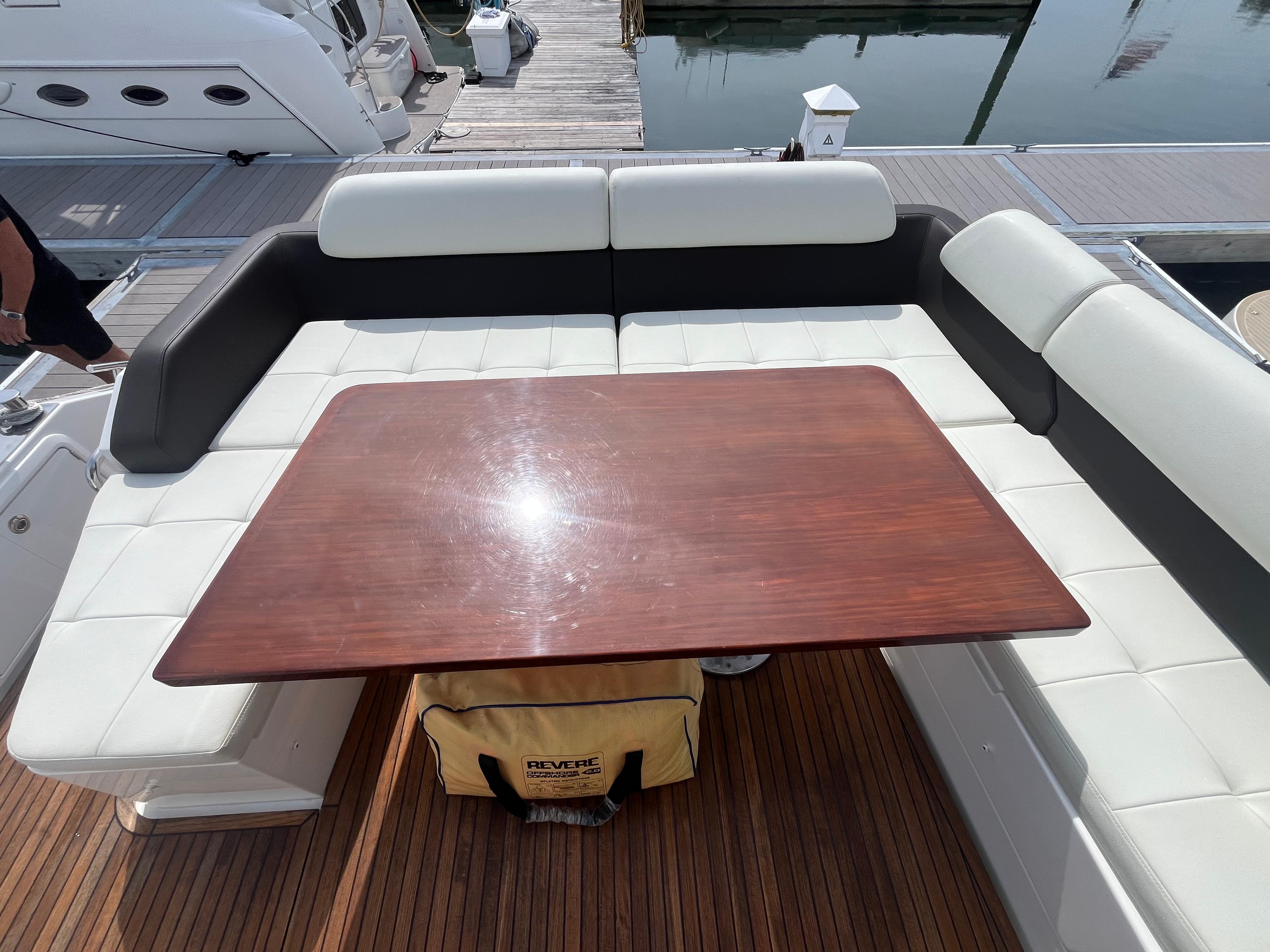 Luxurious seating area on a 2014 Azimut 55S yacht with wooden table and cushioned seats.