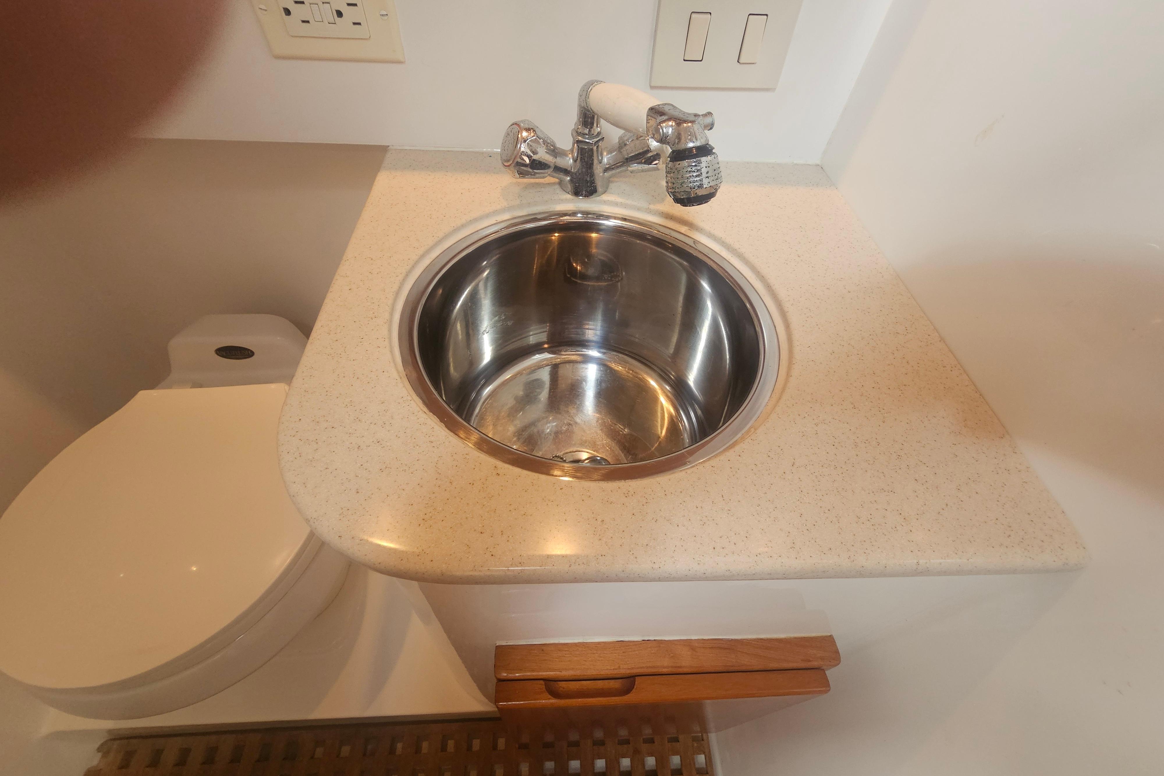 Compact bathroom sink and toilet on a 2003 Topaz 32 Express boat.