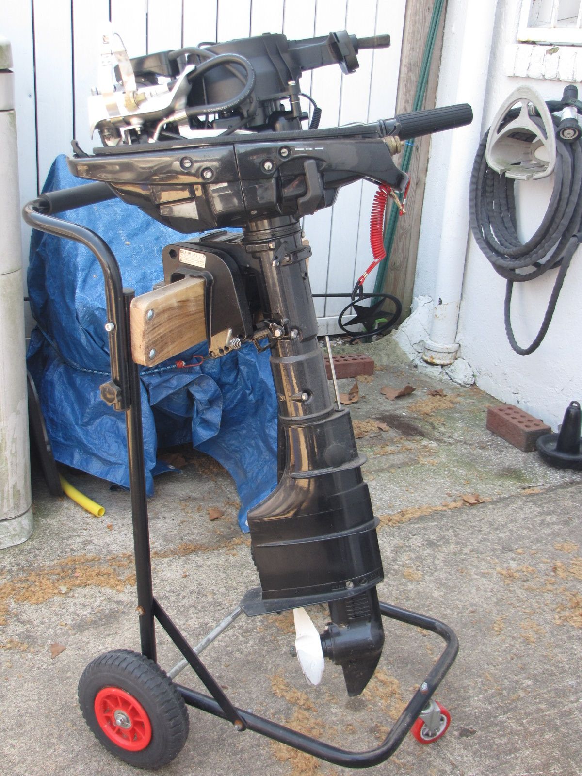 An outboard motor on a rolling stand in a garage.
