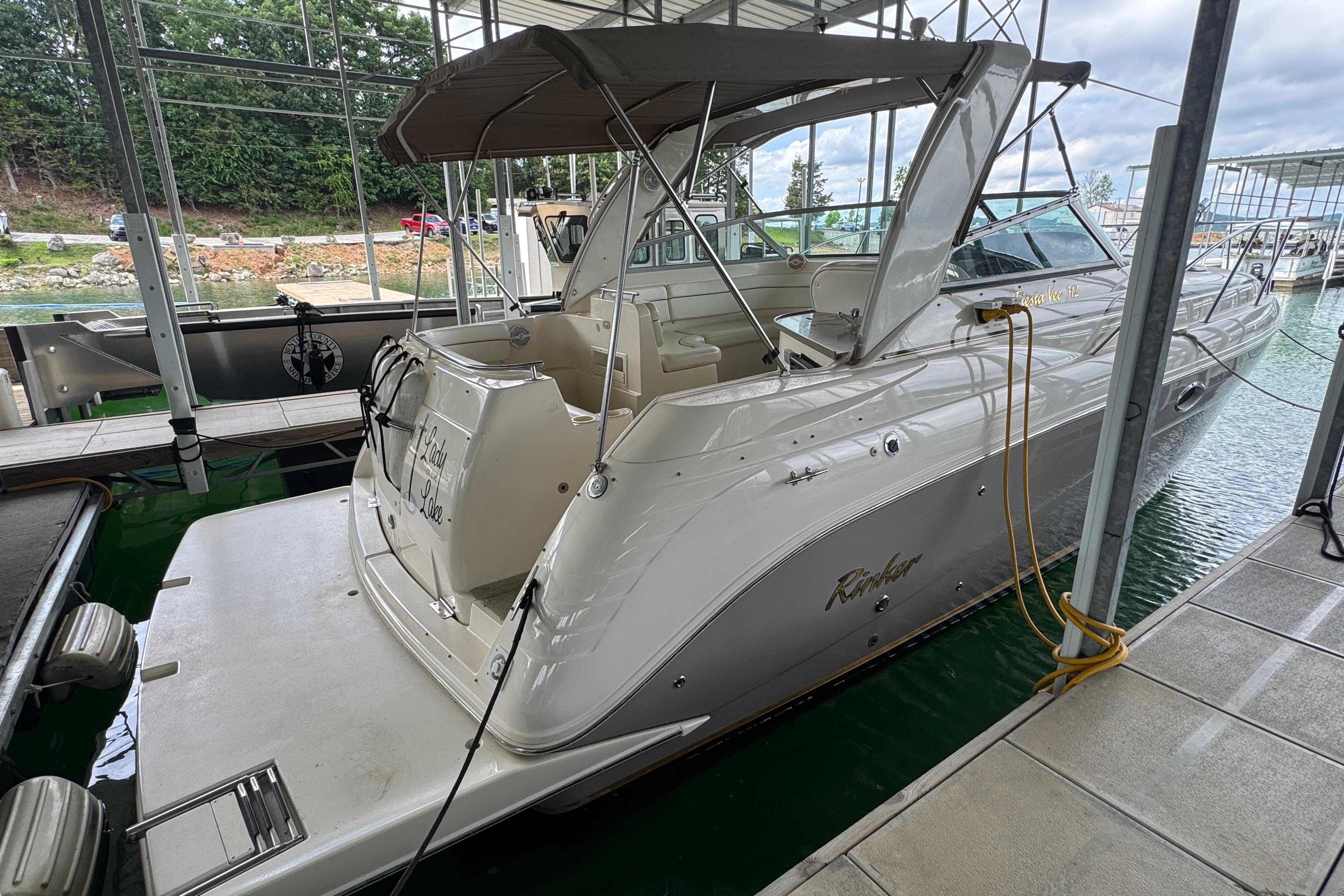 2004 Rinker Fiesta Vee 312 docked in a marina, featuring a sleek design and spacious deck.