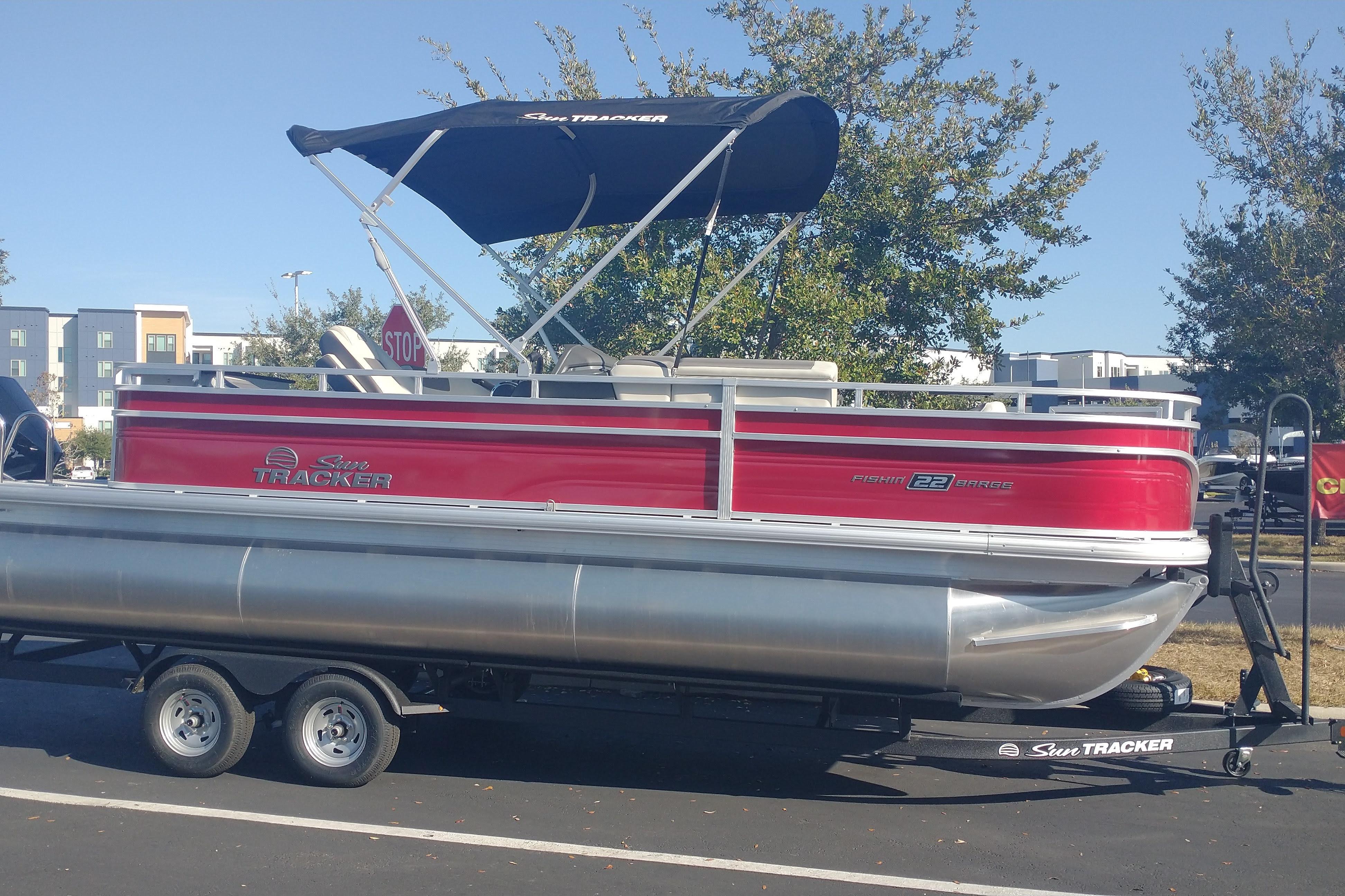 2026 Sun Tracker Fishin' Barge 22 XP3 pontoon boat on trailer, parked outdoors.