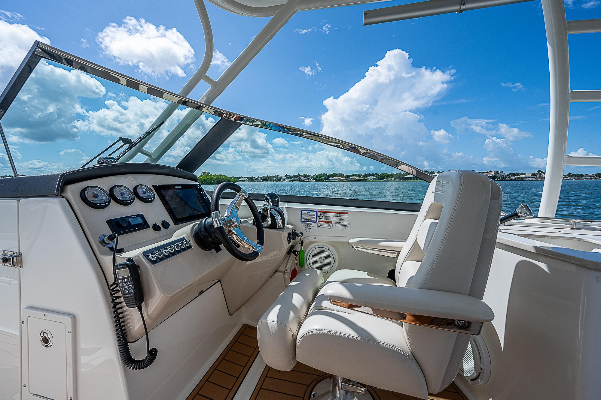 2018 Boston Whaler 270 Vantage boat cockpit with steering wheel and controls, under blue sky.