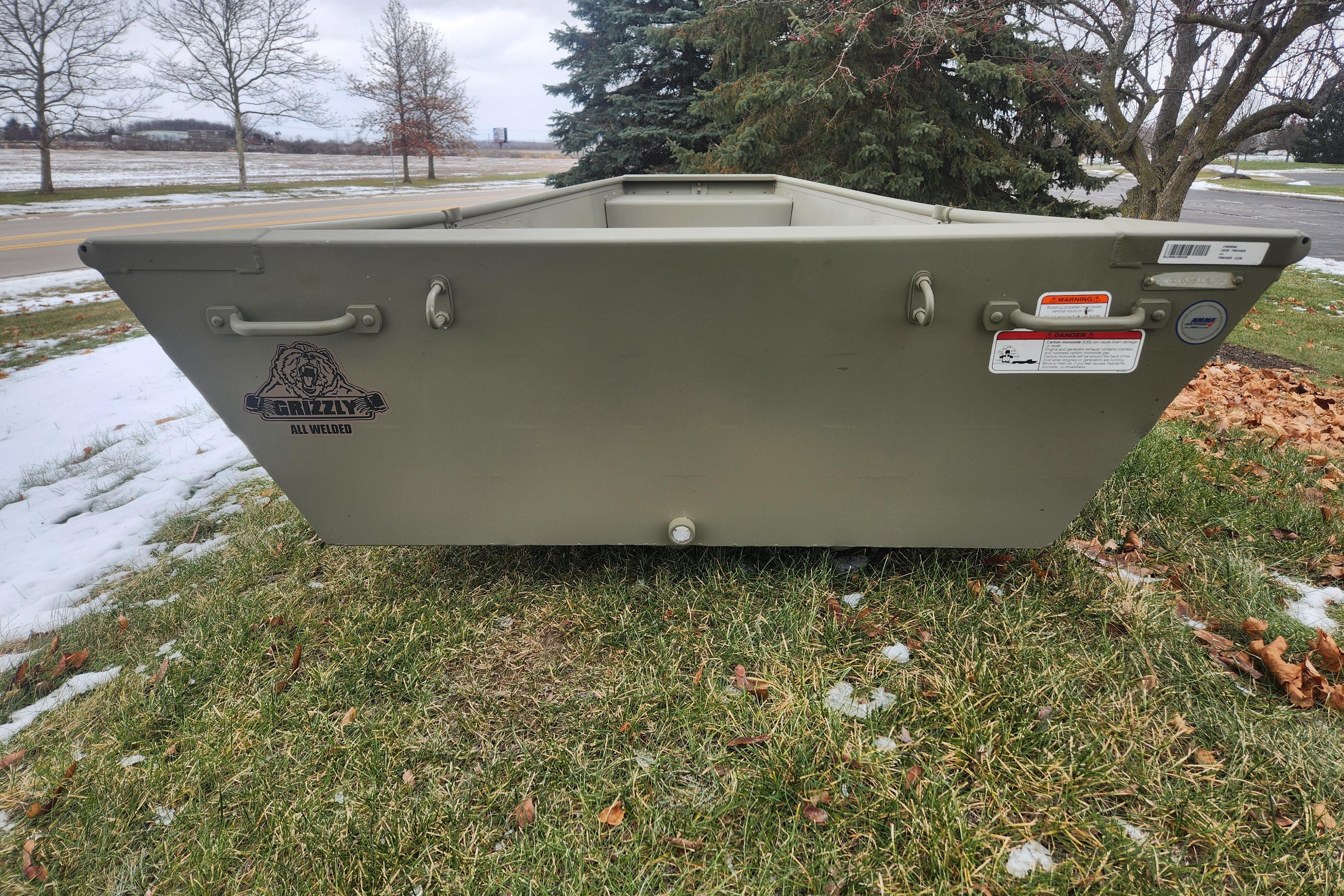 2026 Tracker Grizzly 12 Jon boat on snowy grass, showcasing durable all-welded design.