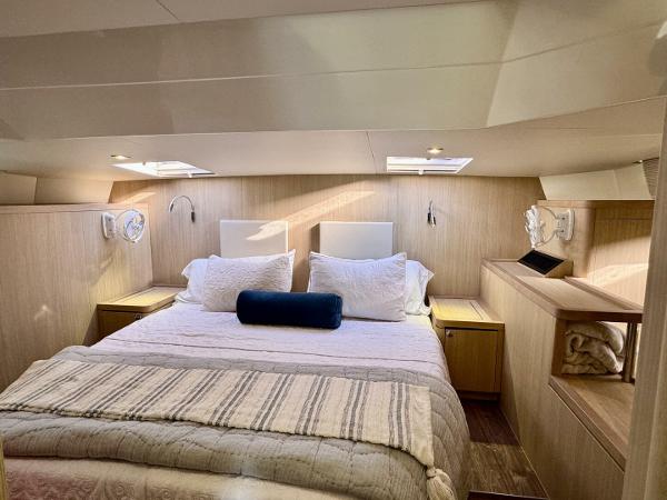 Luxurious bedroom interior of 2022 Aquila 44 yacht with cozy bedding and modern design.