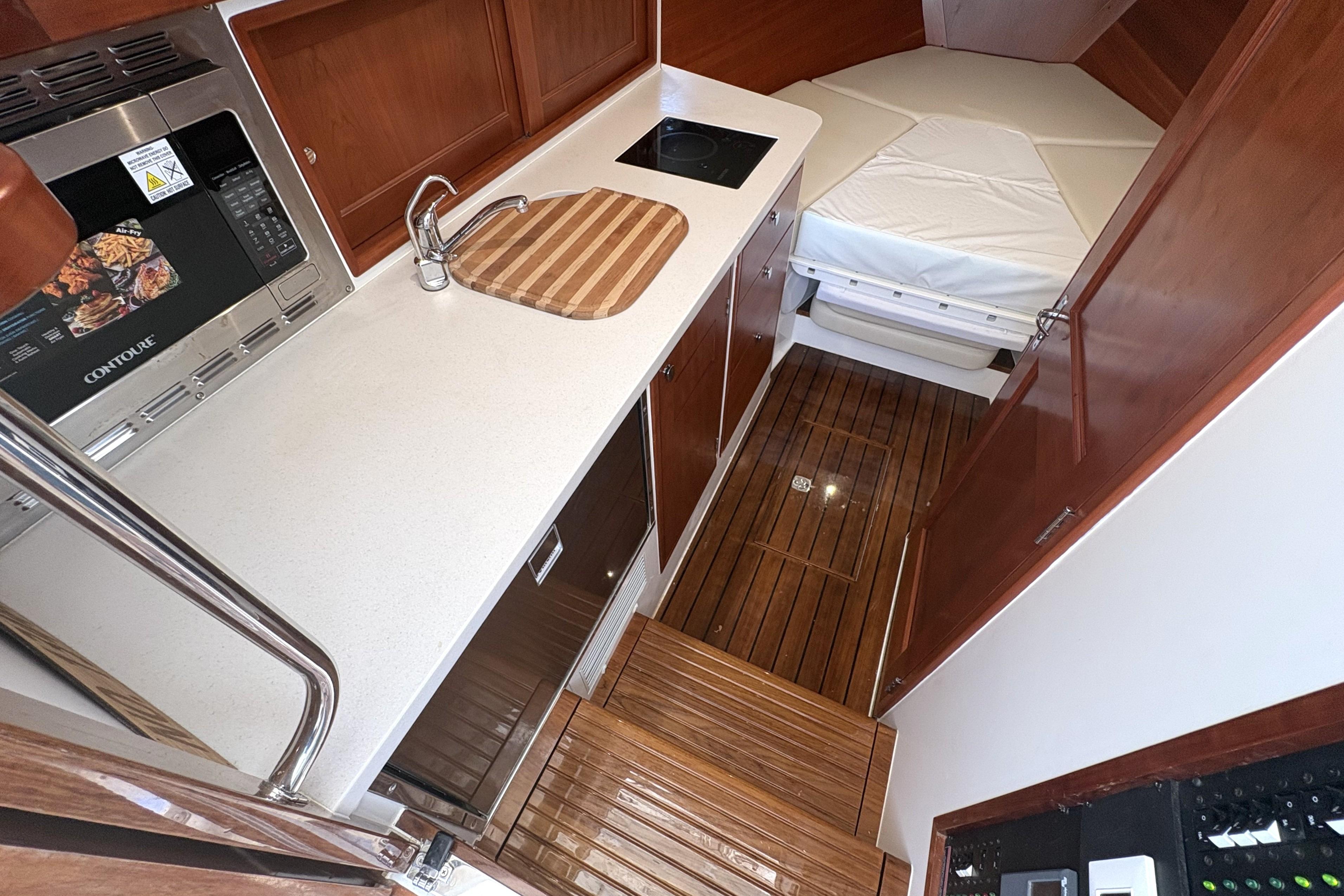 2024 MJM 35z yacht interior with kitchenette, wooden flooring, and cozy sleeping area.