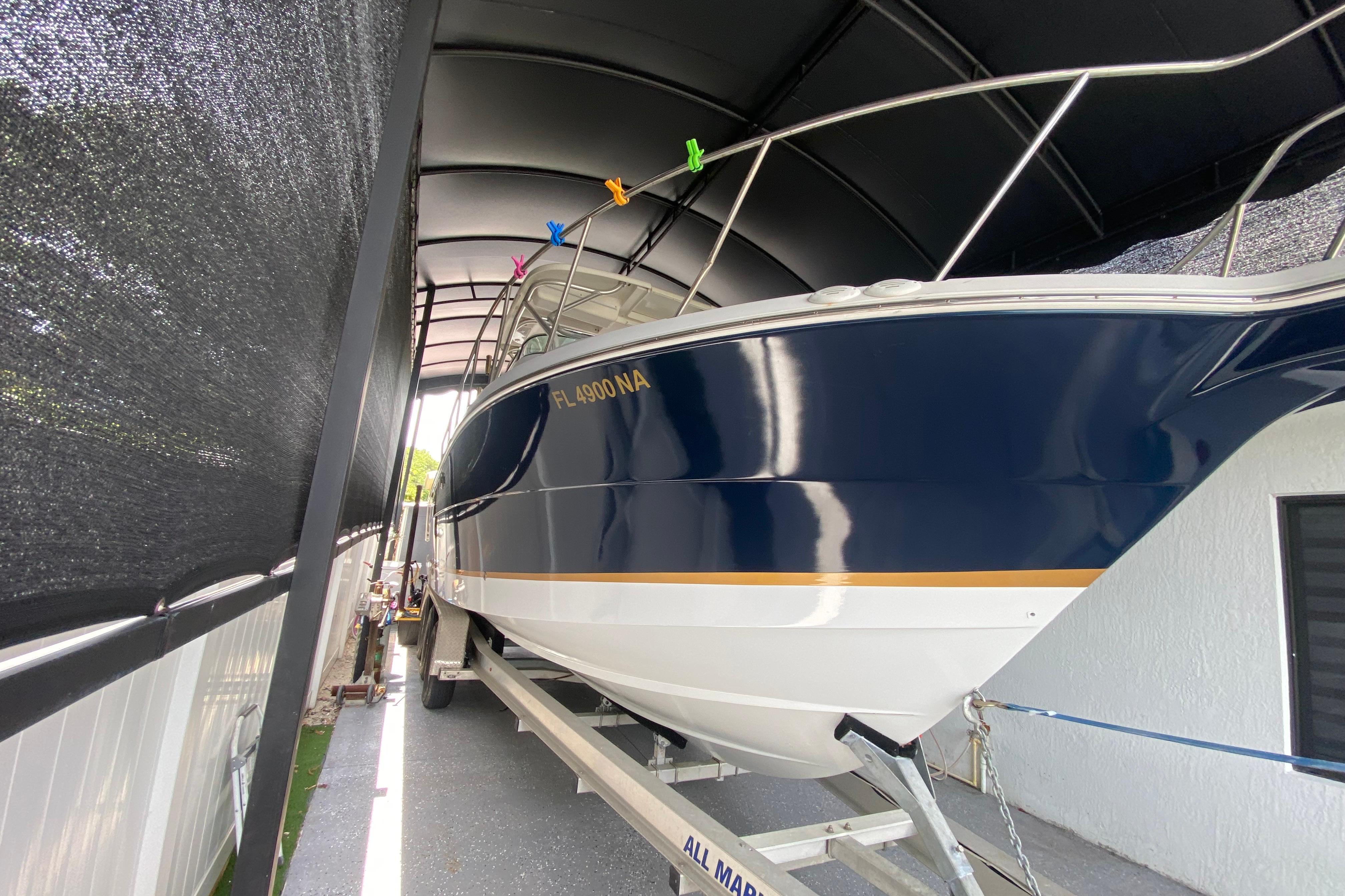 2005 Wellcraft 290 Coastal boat on trailer, under a canopy, side view.