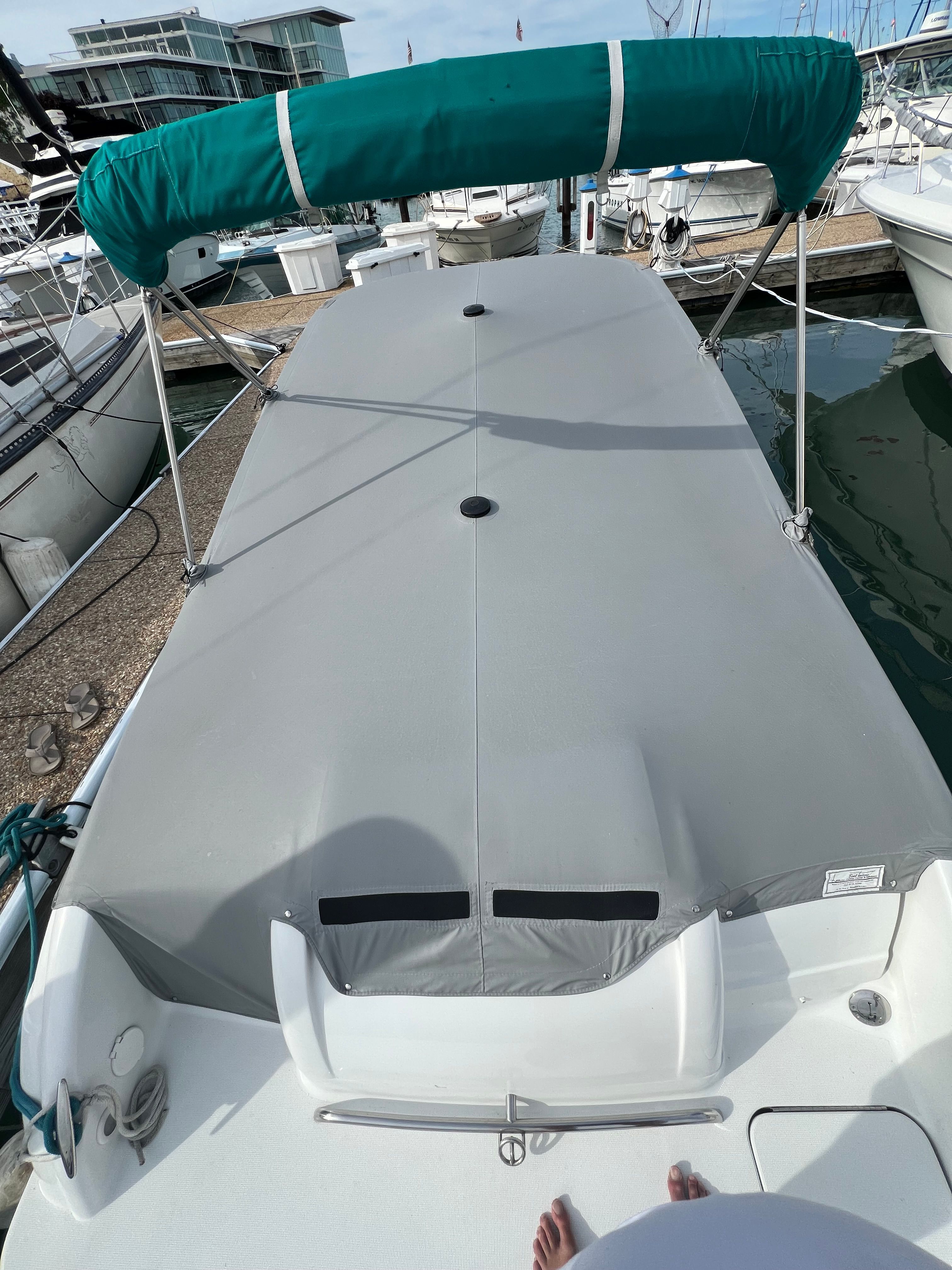 A 2005 Formula 260 Sun Sport with a gray cover and green sunshade at the dock.