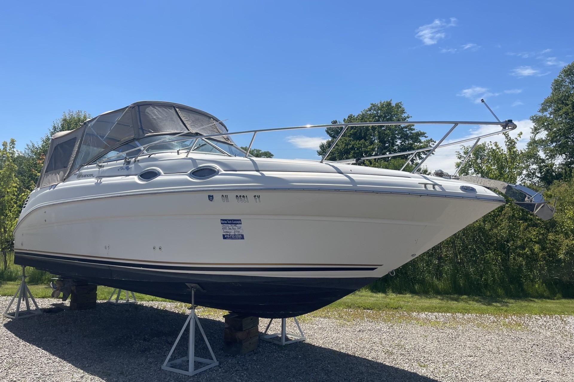 Sea Ray Sundancer 260 boat, 2000 model, on stands, outdoors under clear sky.