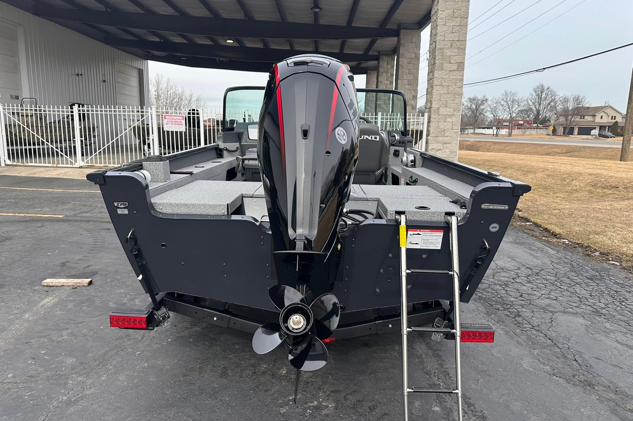 2026 Lund 1775 Adventure Sport boat with outboard motor and ladder, parked outdoors.