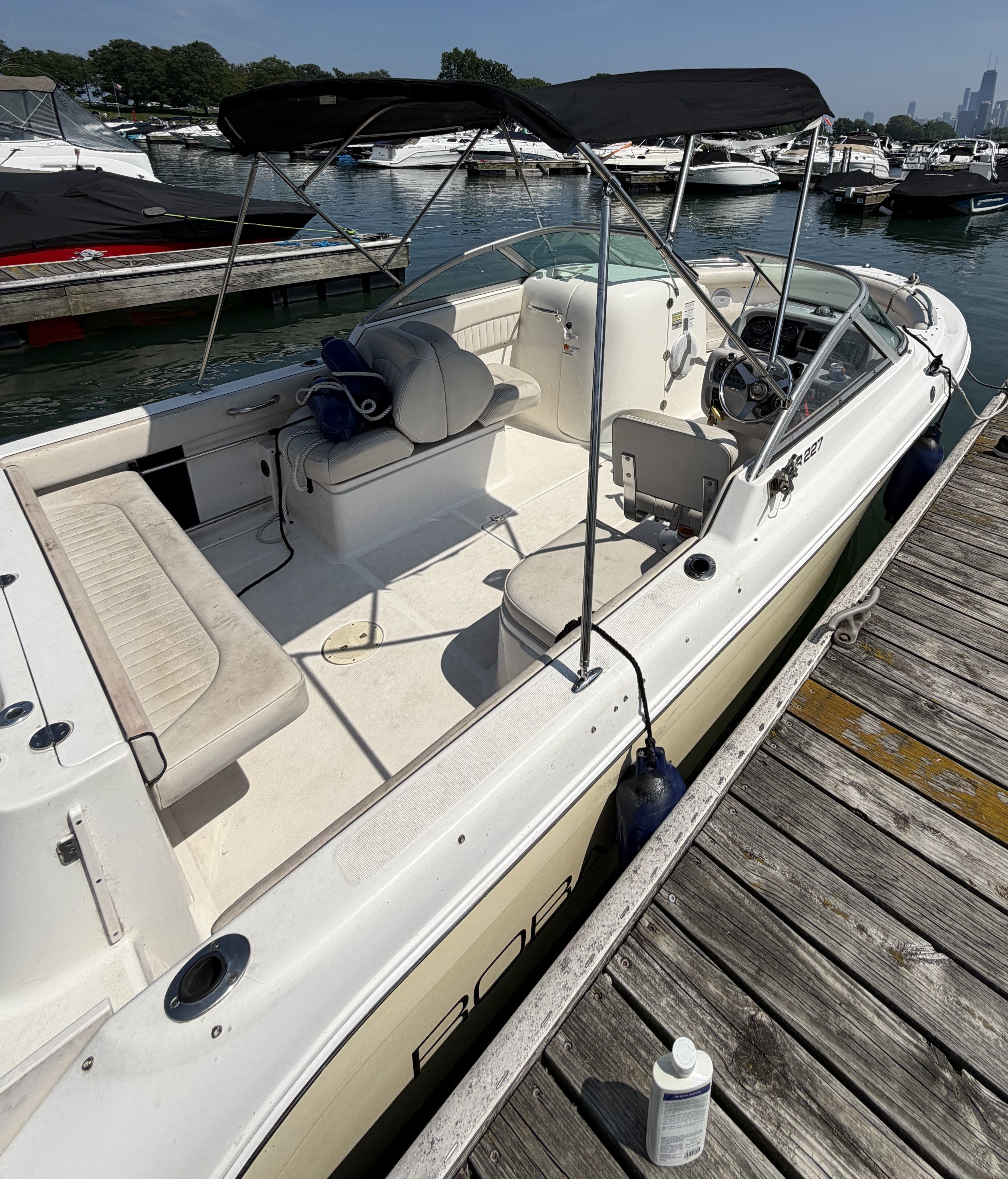 A 2005 Robalo R227 Dual Console boat docked at a wooden pier in a marina.