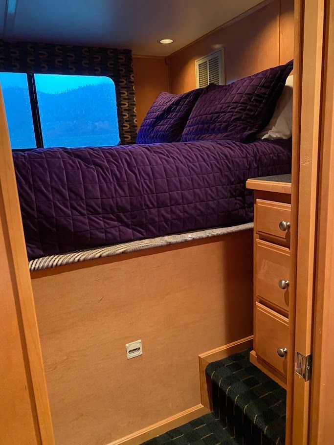 Bedroom in a 2006 Summersun Houseboat 16x68 with purple bedding.